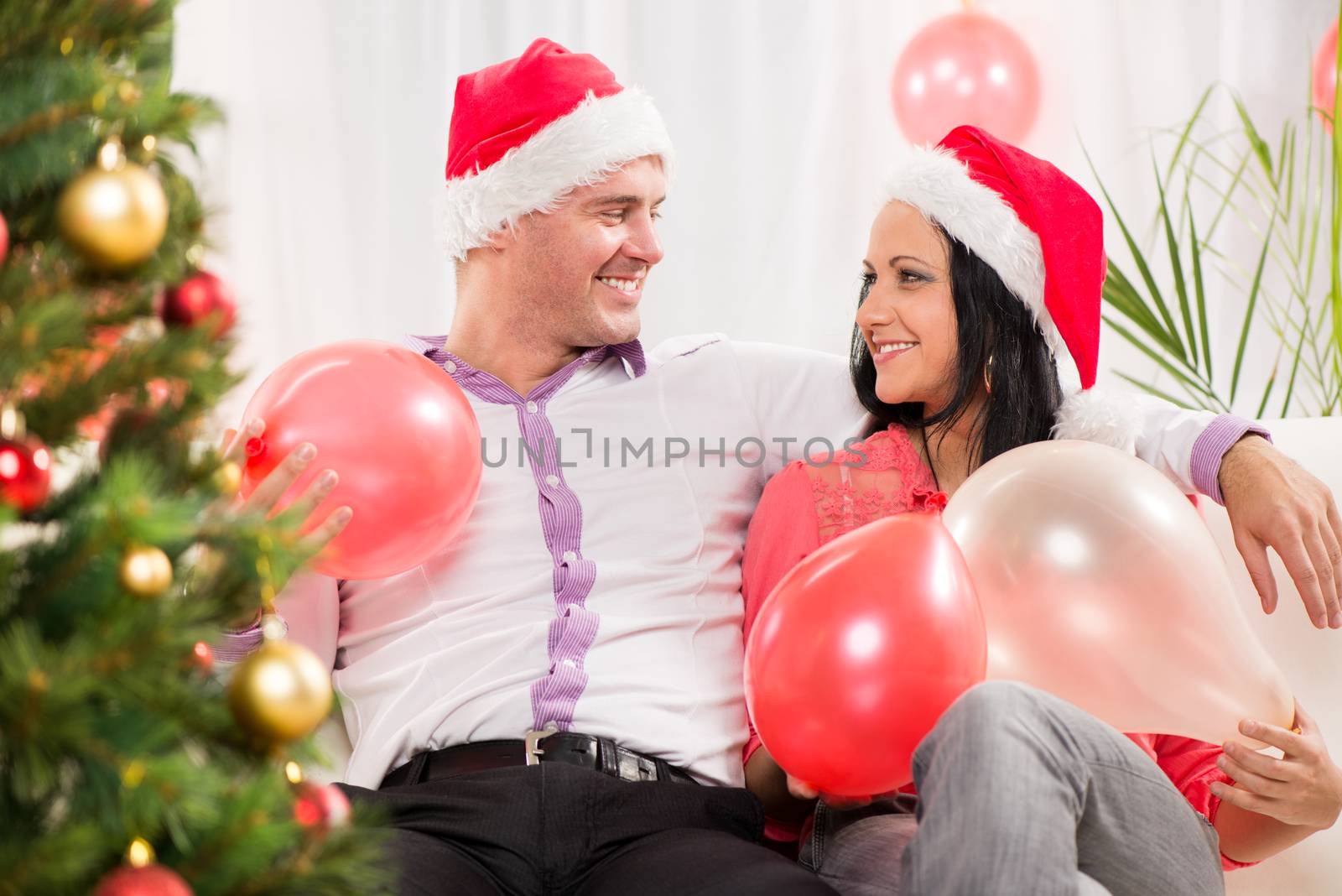 Beautiful happy Christmas couple in home with balloons.