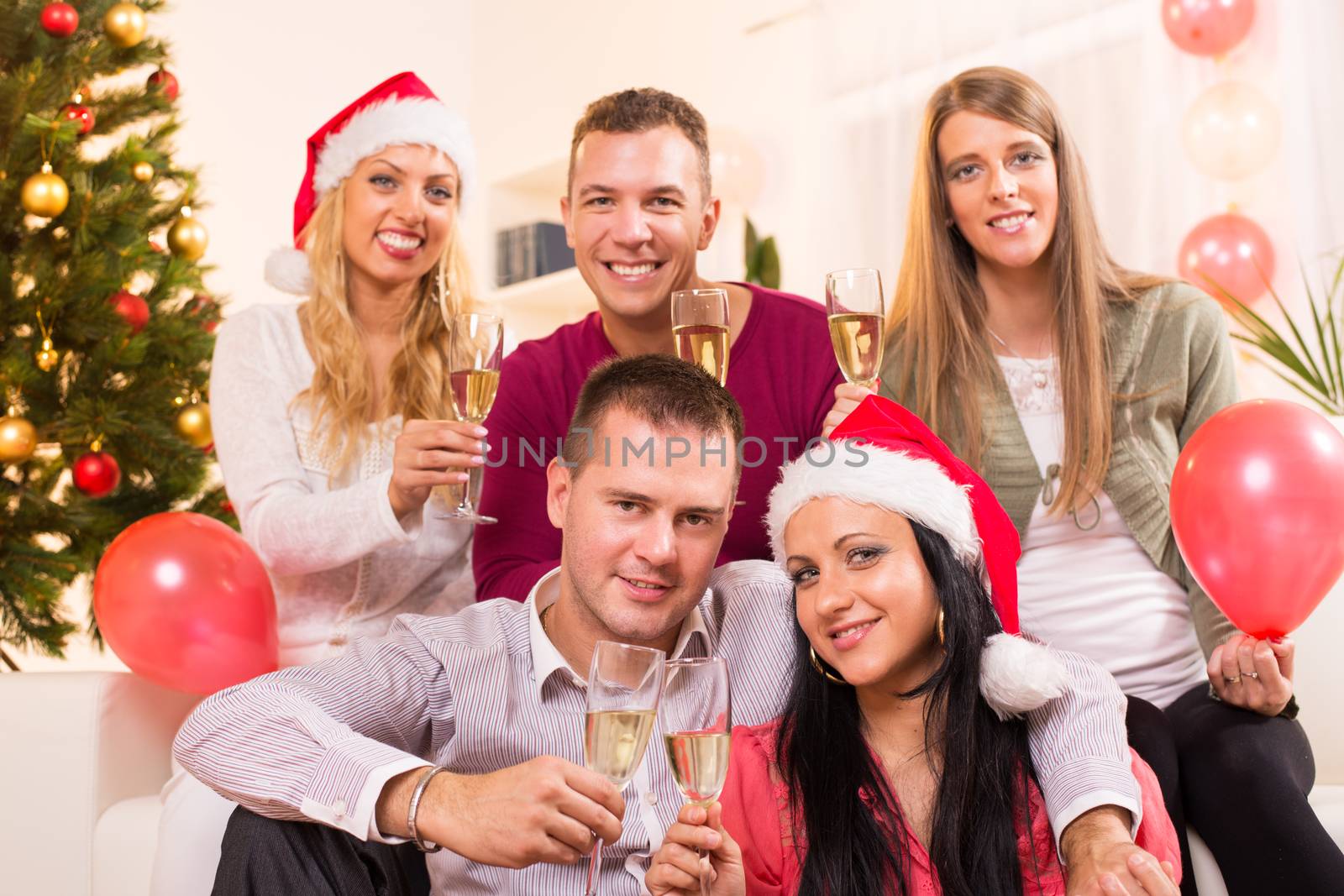 Happy friends Celebrating Christmas or New Year with glass of champagne in home interior.