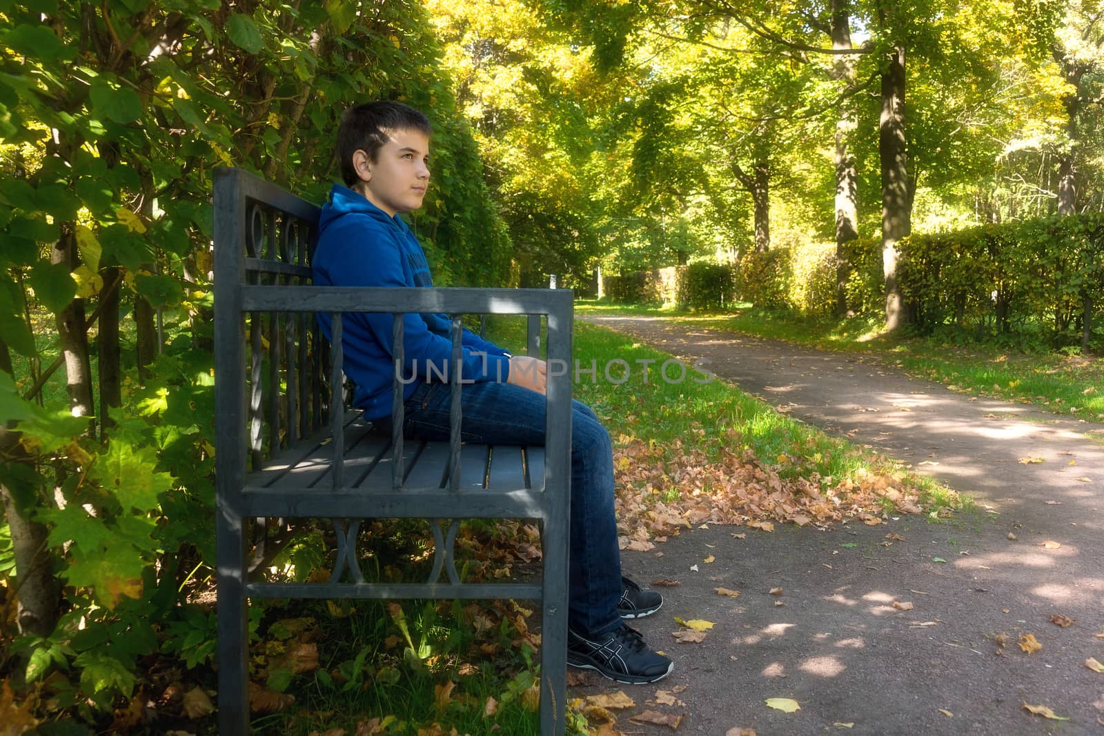 The photo depicts a boy sitting on a bench