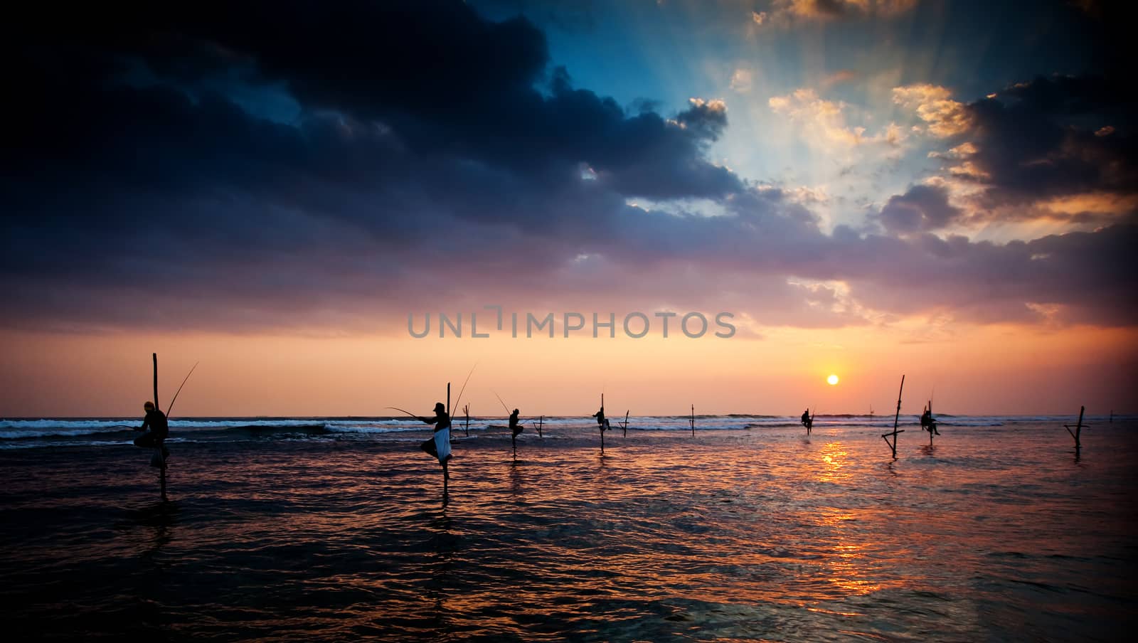 Silhouettes of the traditional stilt fishermen at the sunset near Galle in Sri Lanka