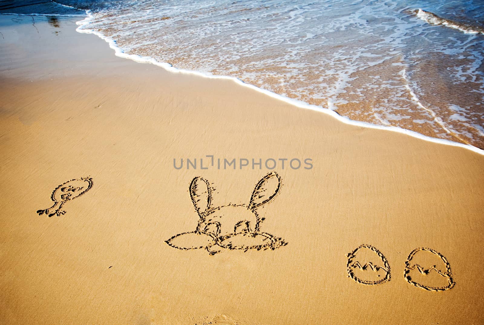 Easter bunny and eggs drawn in sand on tropical beach