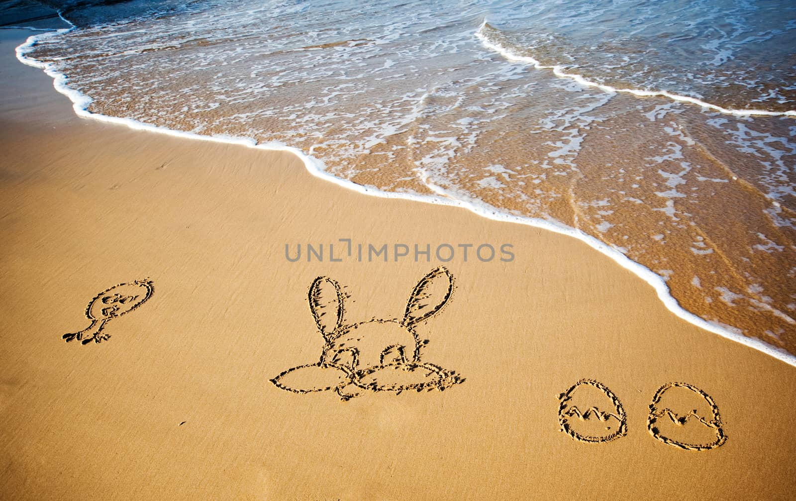 Easter bunny and eggs drawn in sand on tropical beach