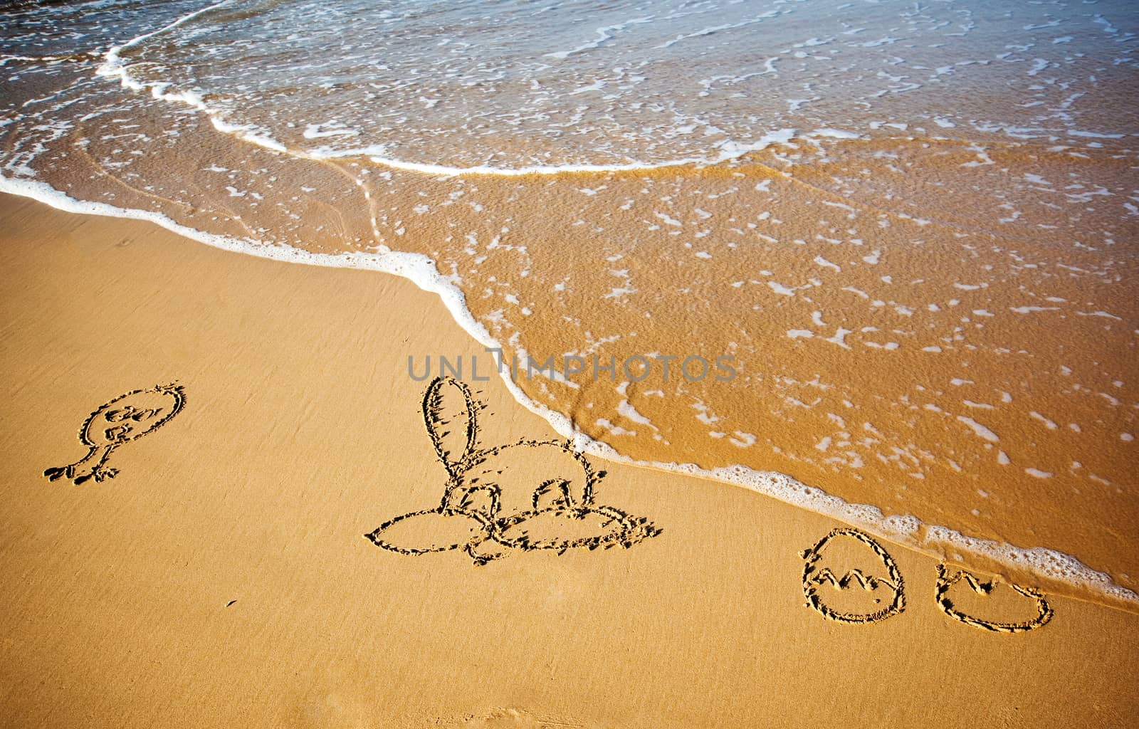 Easter bunny and eggs drawn in sand on tropical beach