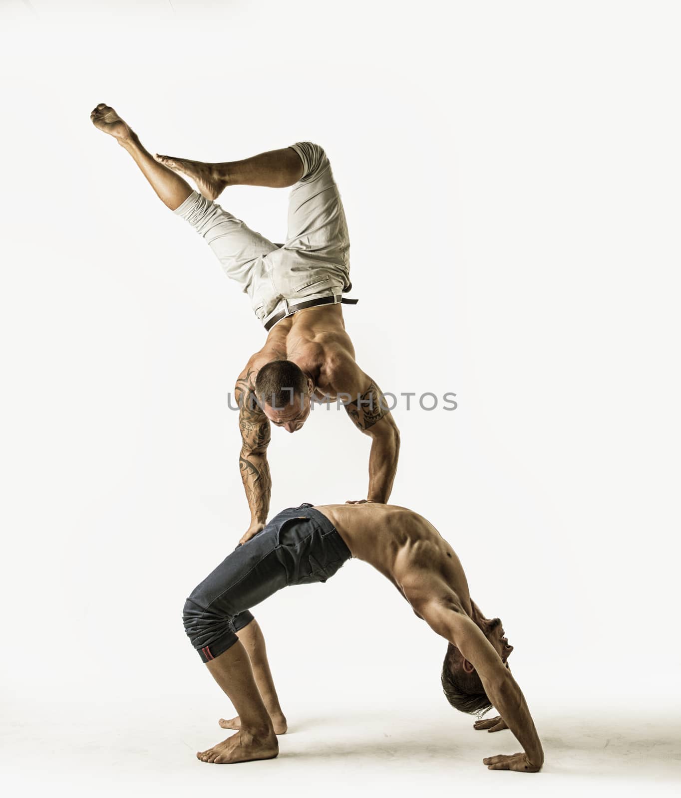 Muscular Shirtless Male Acrobatic Dancers Balancing on Top of Each Other in Studio with White Background