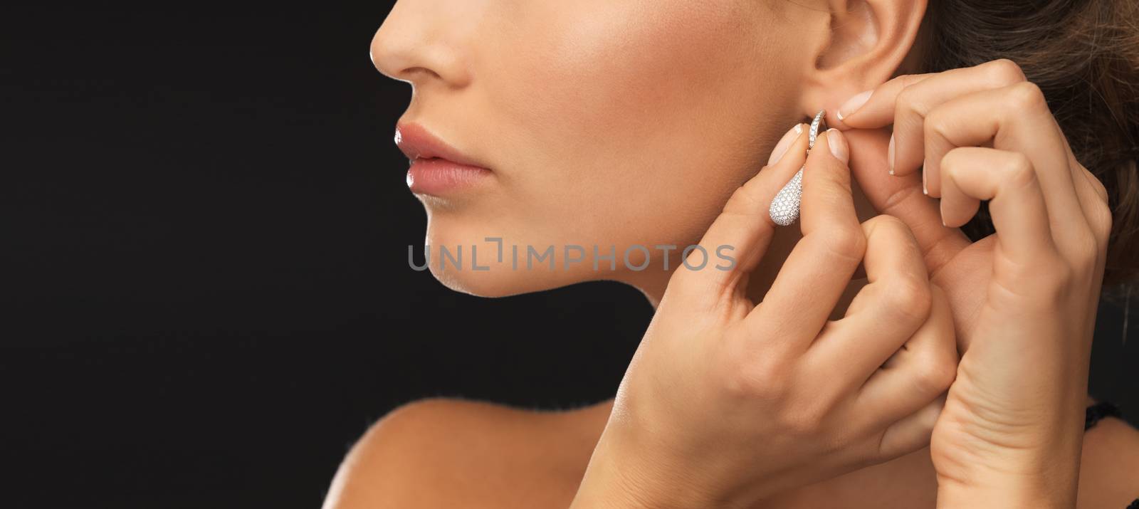 woman wearing shiny diamond earrings by dolgachov