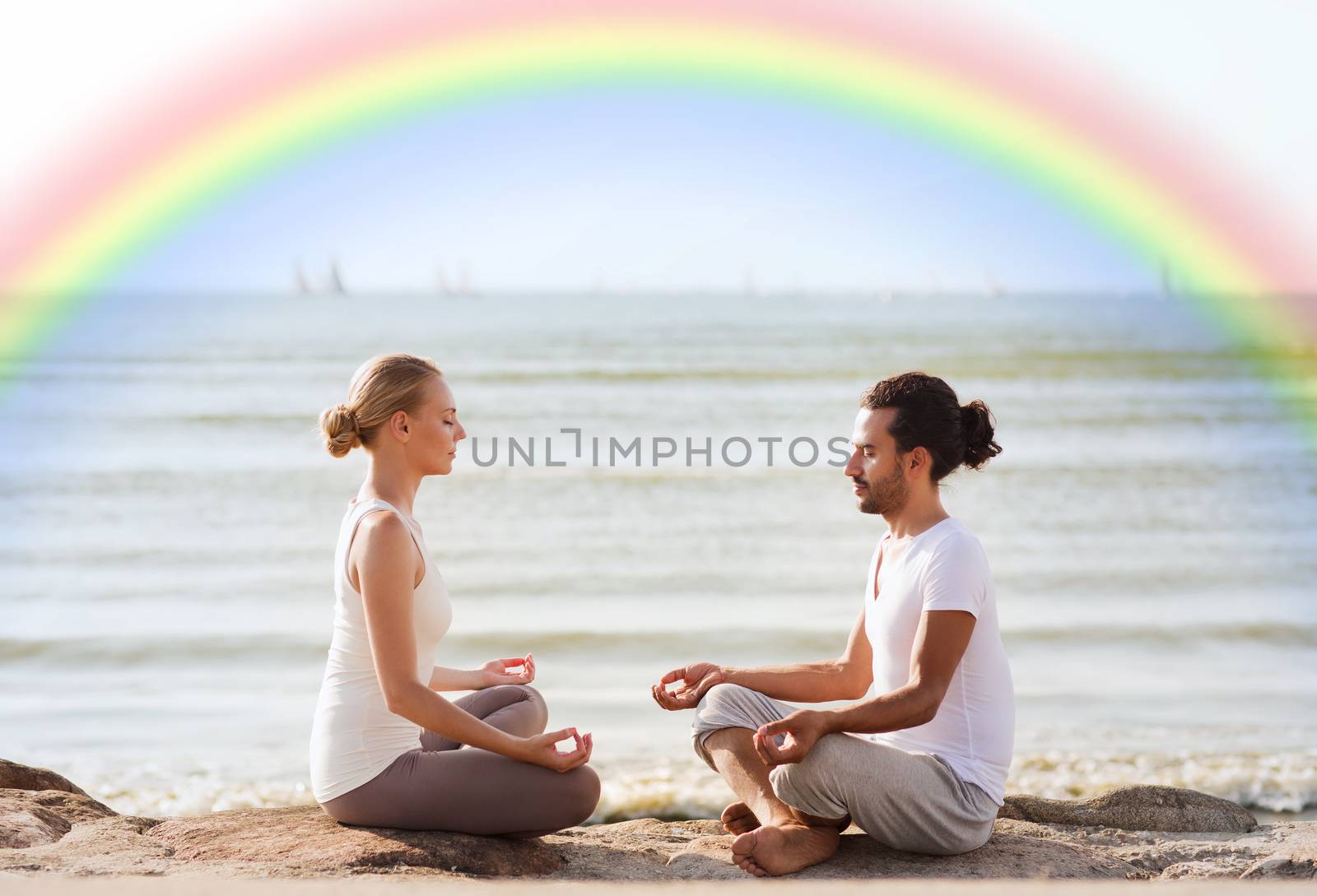 fitness, sport, people, yoga and lifestyle concept - happy couple meditating in lotus pose on summer beach