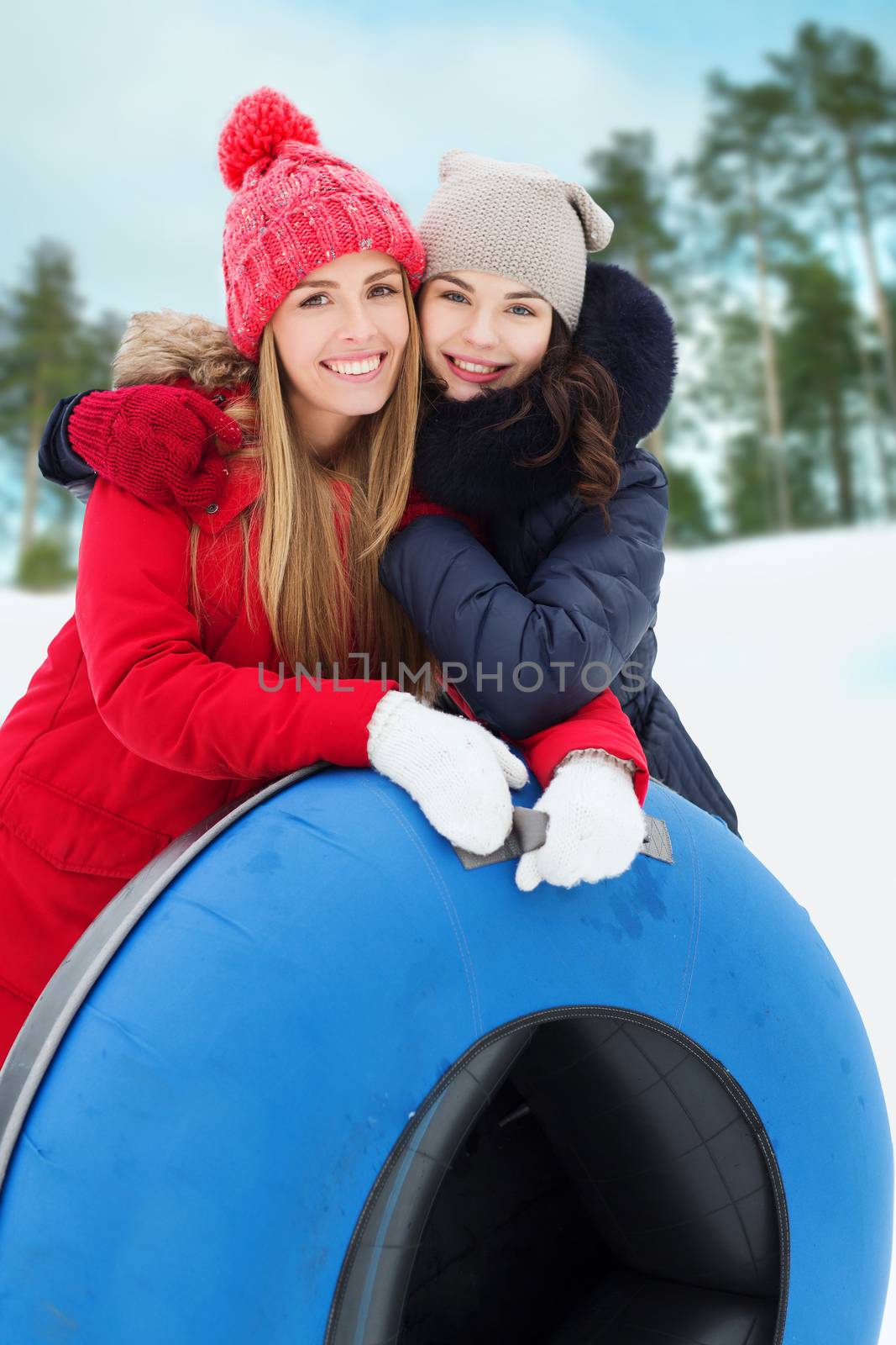 happy girl friends with snow tubes outdoors by dolgachov