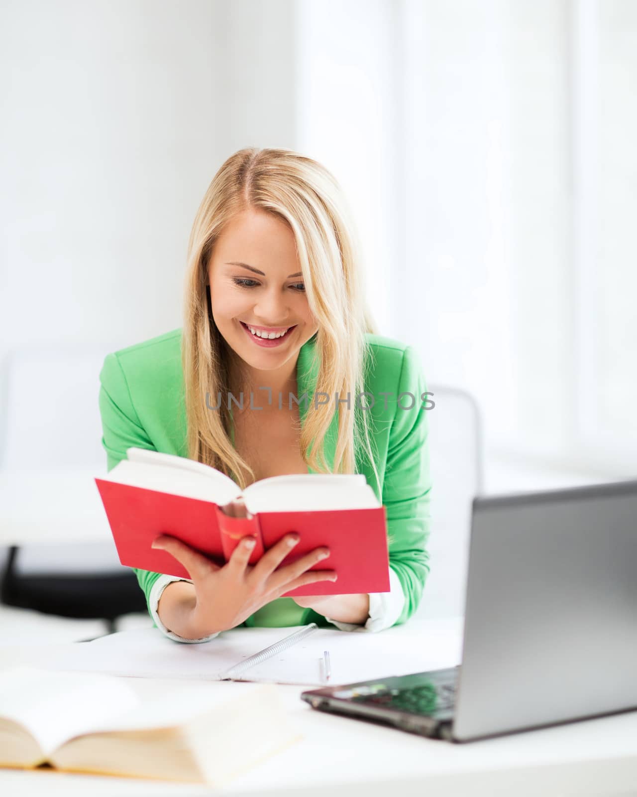 smiling student girl reading book in college by dolgachov