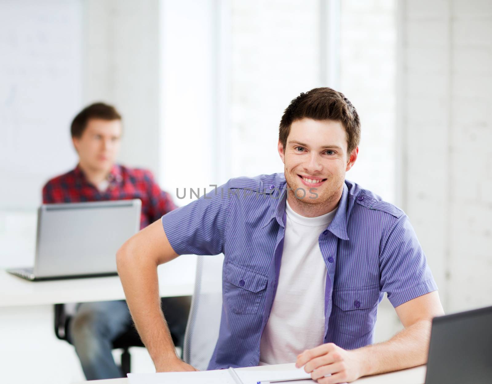 education - group of smiling students with laptops at school