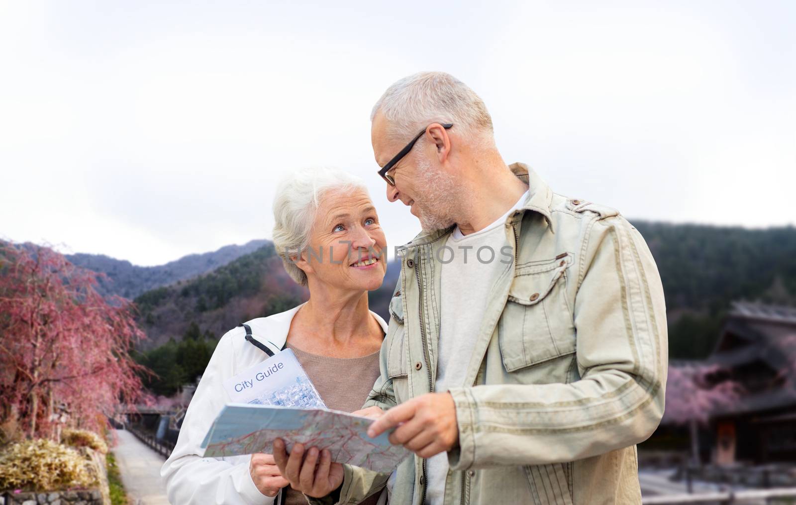 family, age, tourism, travel and people concept - senior couple with map and over asian village and mountains landscape background