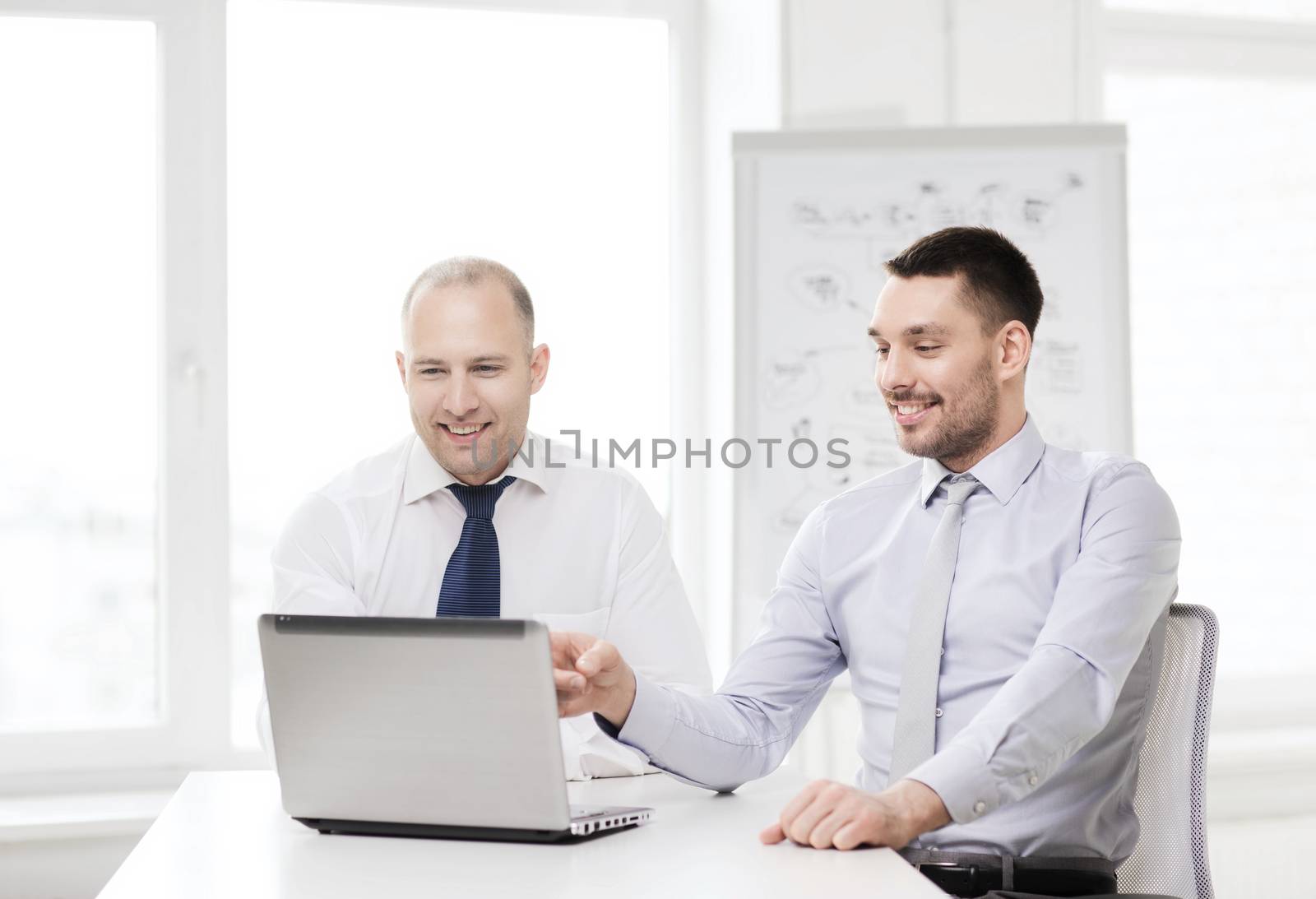 two smiling businessmen with laptop in office by dolgachov