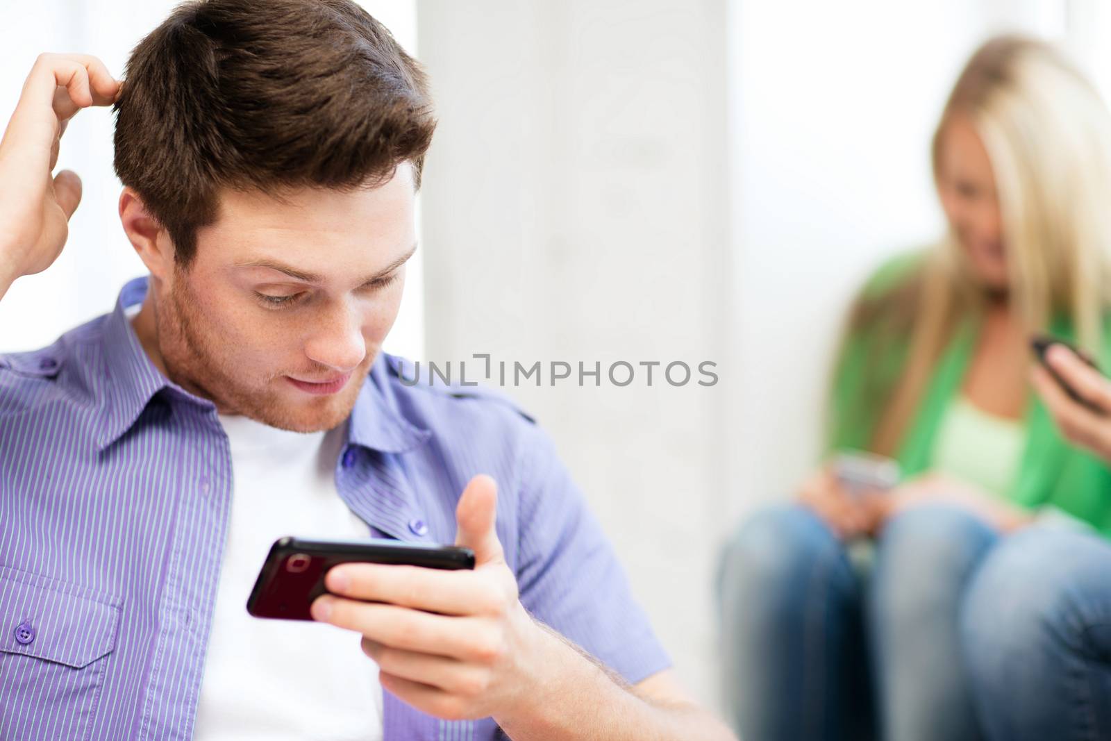 technology concept - student looking at phone and writing something