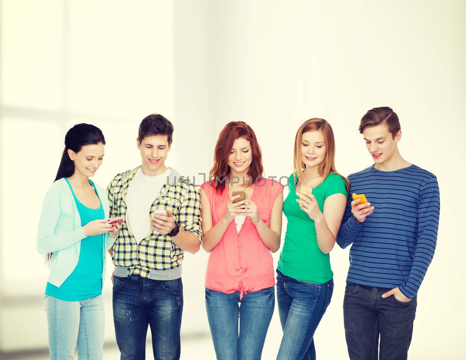 smiling students with smartphones by dolgachov