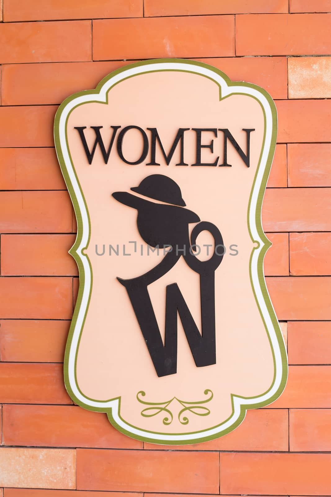 Modern sign on the brick wall of toilet. Text "women"