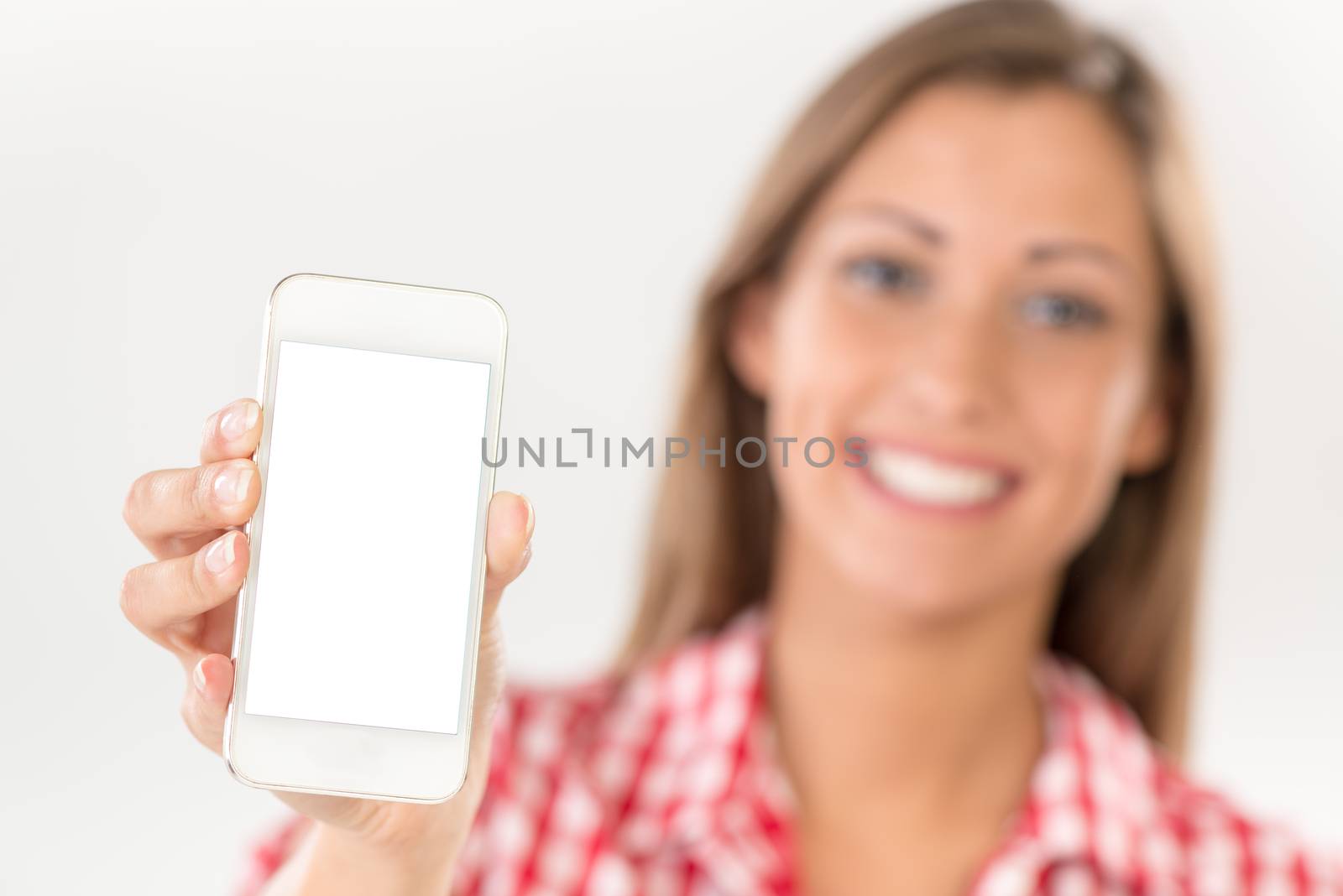 Beautiful young woman showing white smartphone with blank screen. Selective focus. Focus on phone, on foreground.