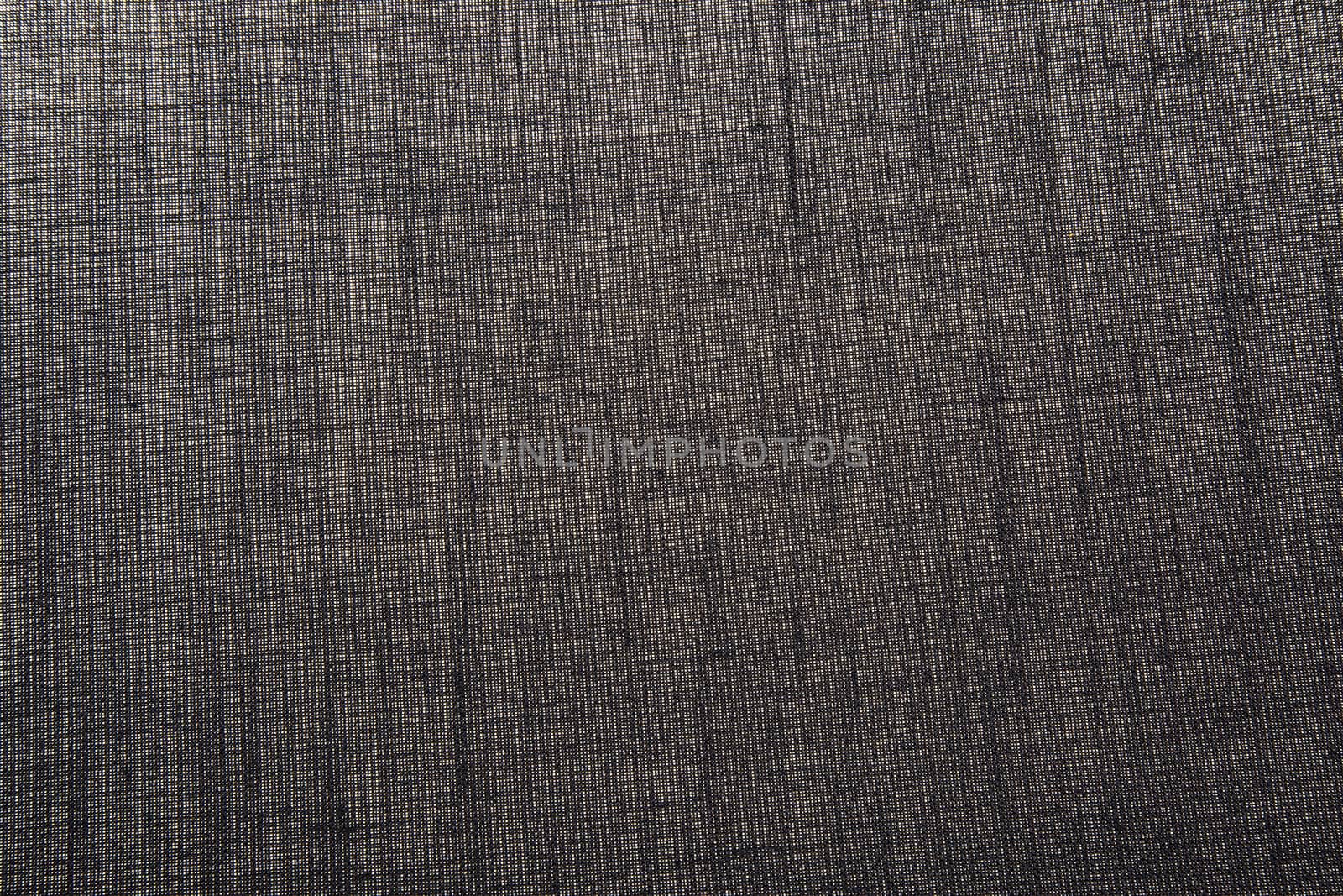 Sheet dark gray cotton material with a distinct texture lit from below.Horizontal view.
