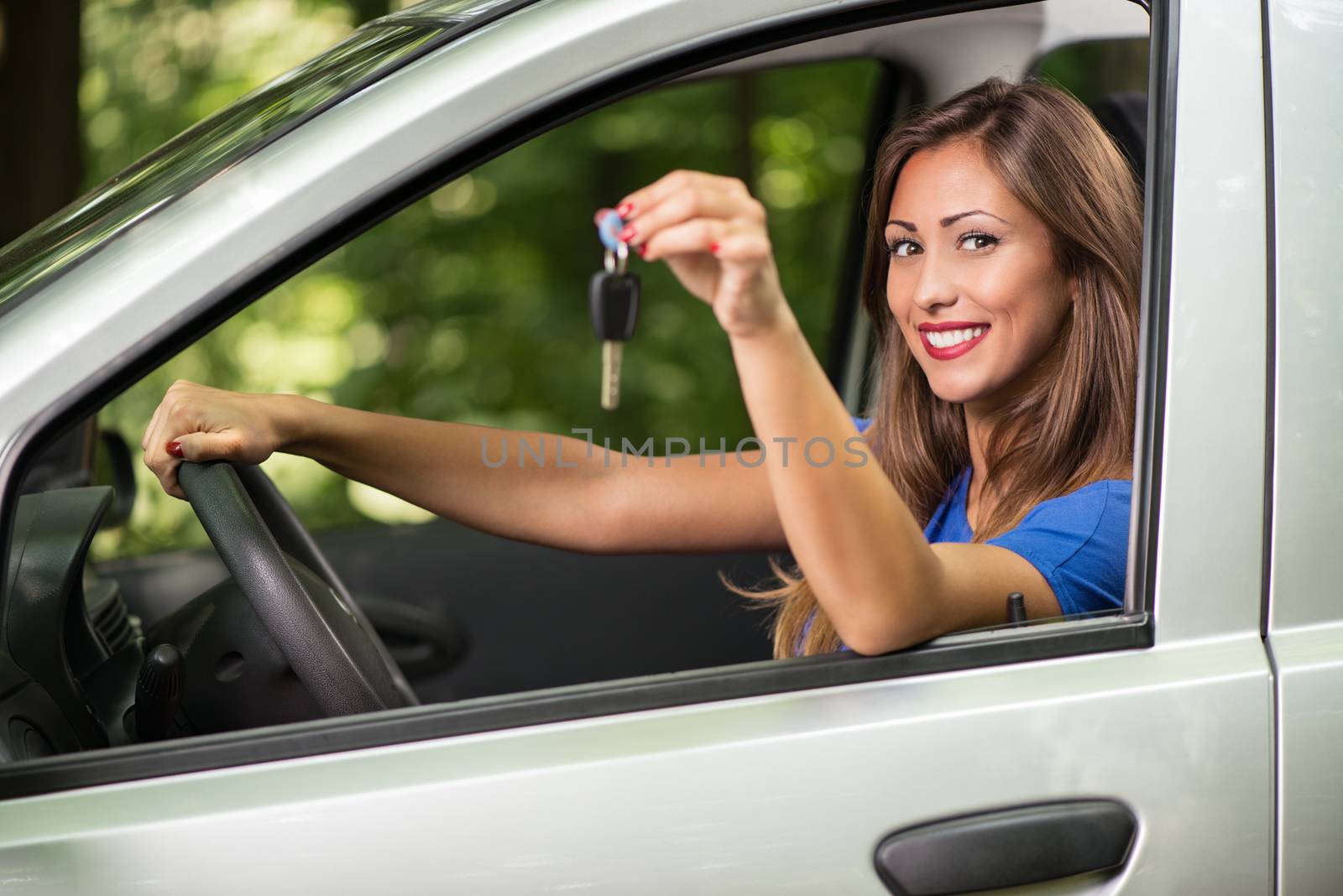 Young beautiful car driver woman smiling and showing car keys. Looking at camera.