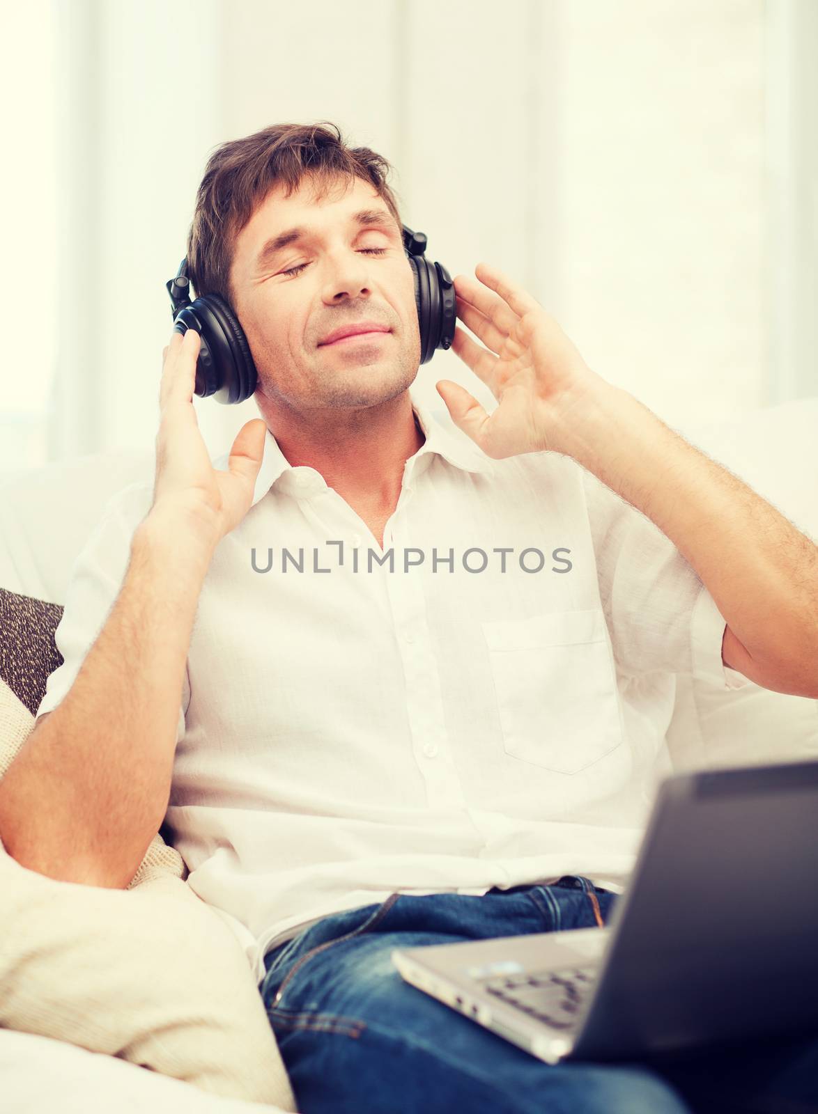 technology, leisure and lifestyle concept - happy man with headphones listening to music at home