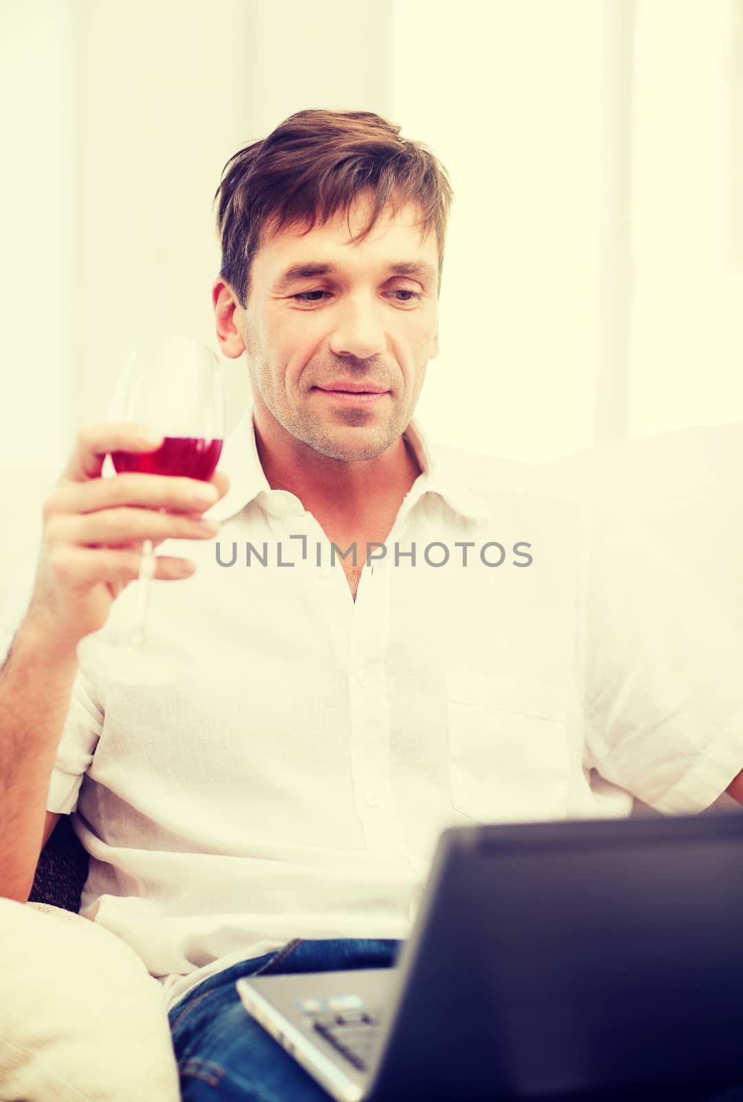 technology, business, leisure, drinks, retirement and lifestyle concept - happy man with laptop computer and glass of rose wine at home