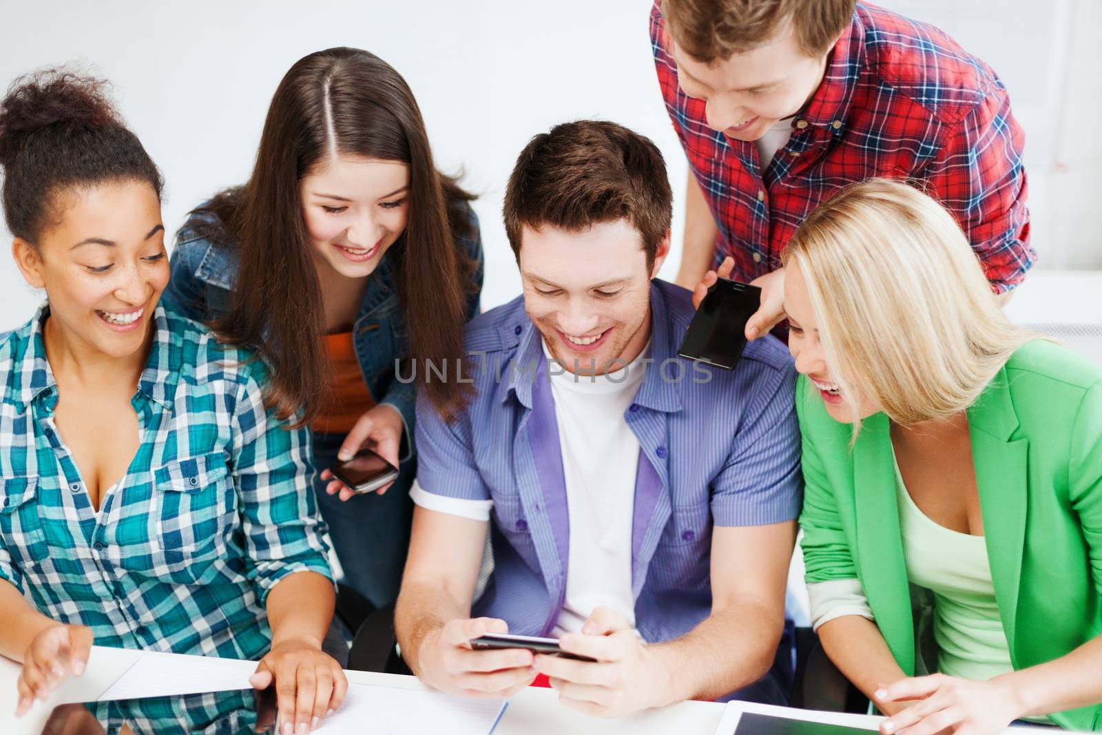 education concept - group of students looking into smartphone at school