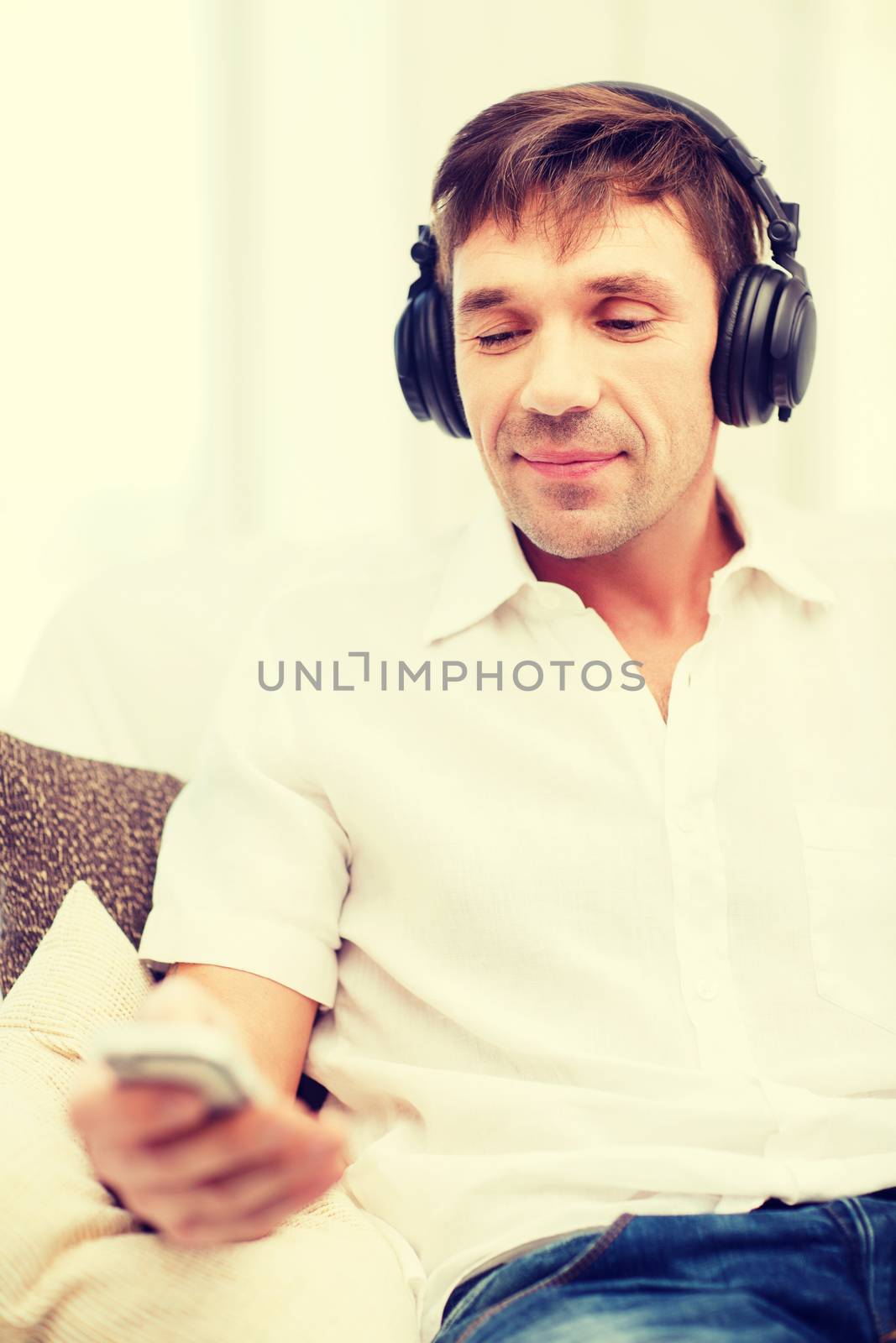 technology, leisure and lifestyle concept - happy man with headphones listening to music at home