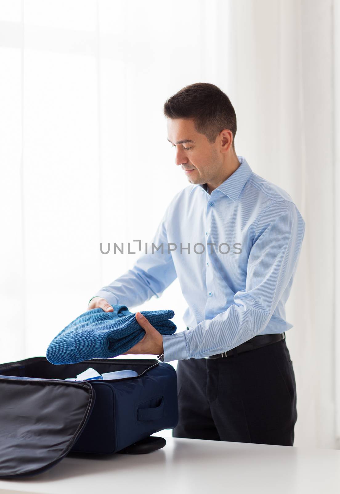 businessman packing clothes into travel bag by dolgachov