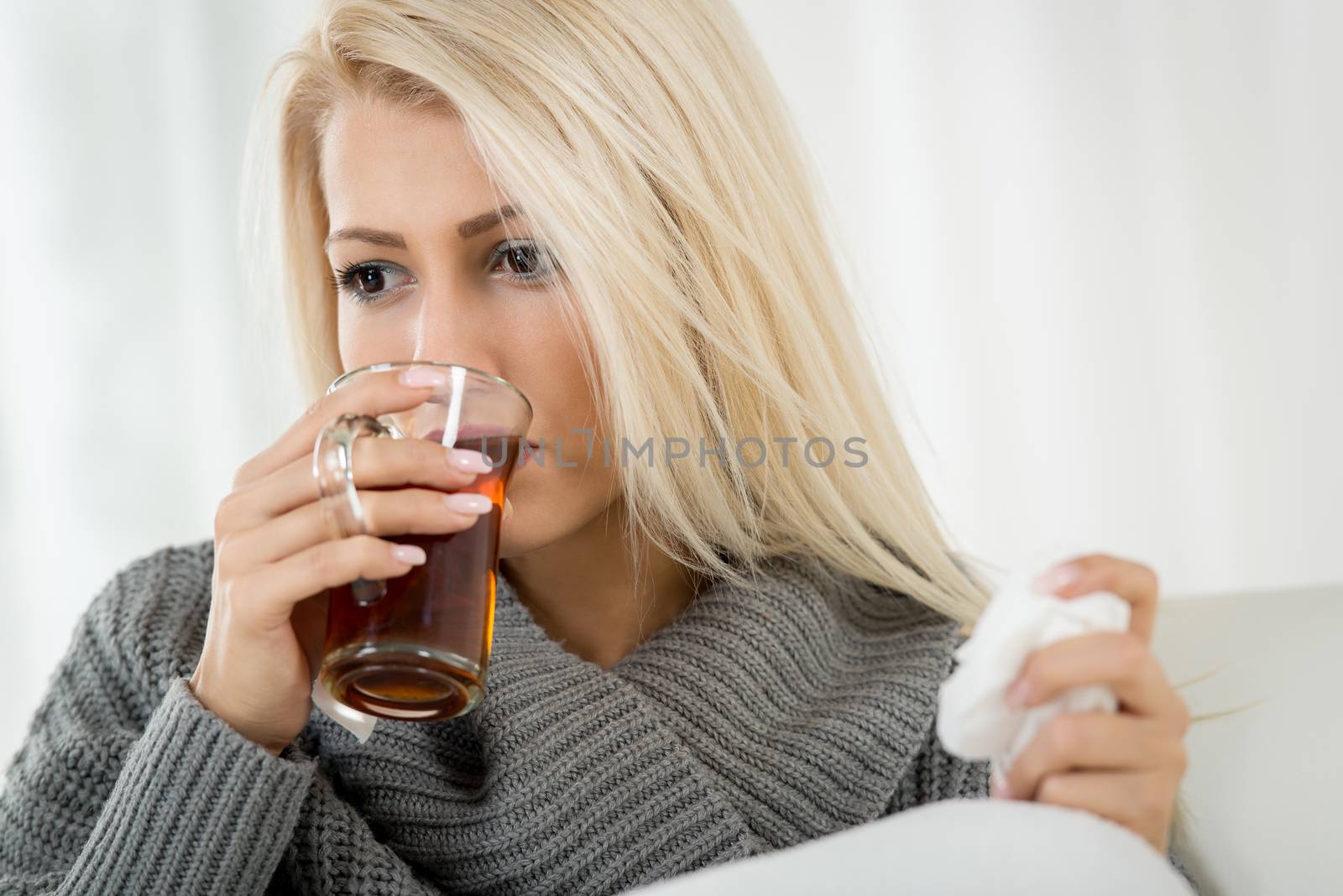 A beautiful girl drinking a tea and holding a handkerchief.