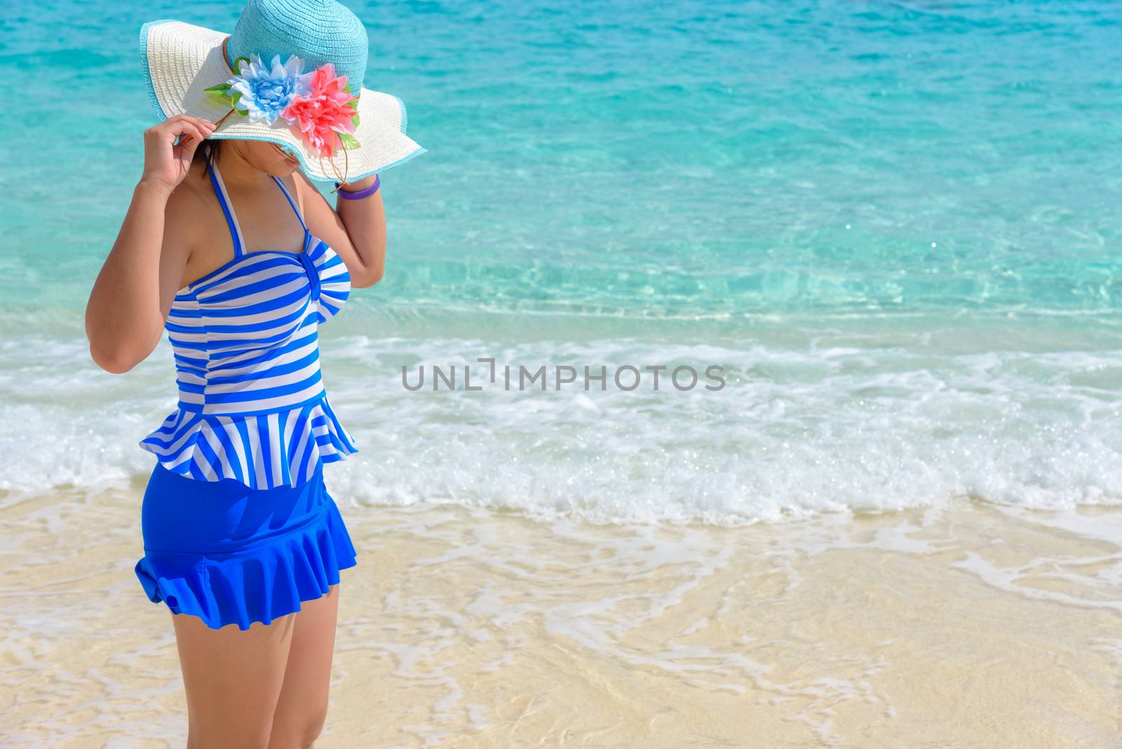 Tourist girl in a blue white striped swimsuit standing with happiness on the beautiful beach and sea during summer at Koh Miang Island, Mu Ko Similan National Park, Phang Nga province, Thailand