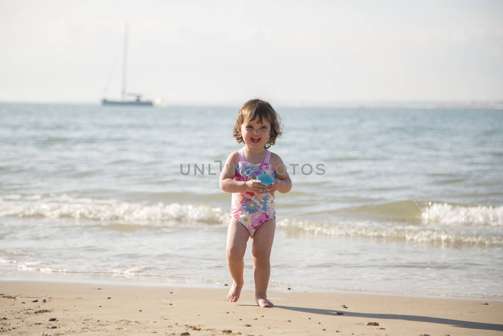 Toddler walking on sand away from sea front