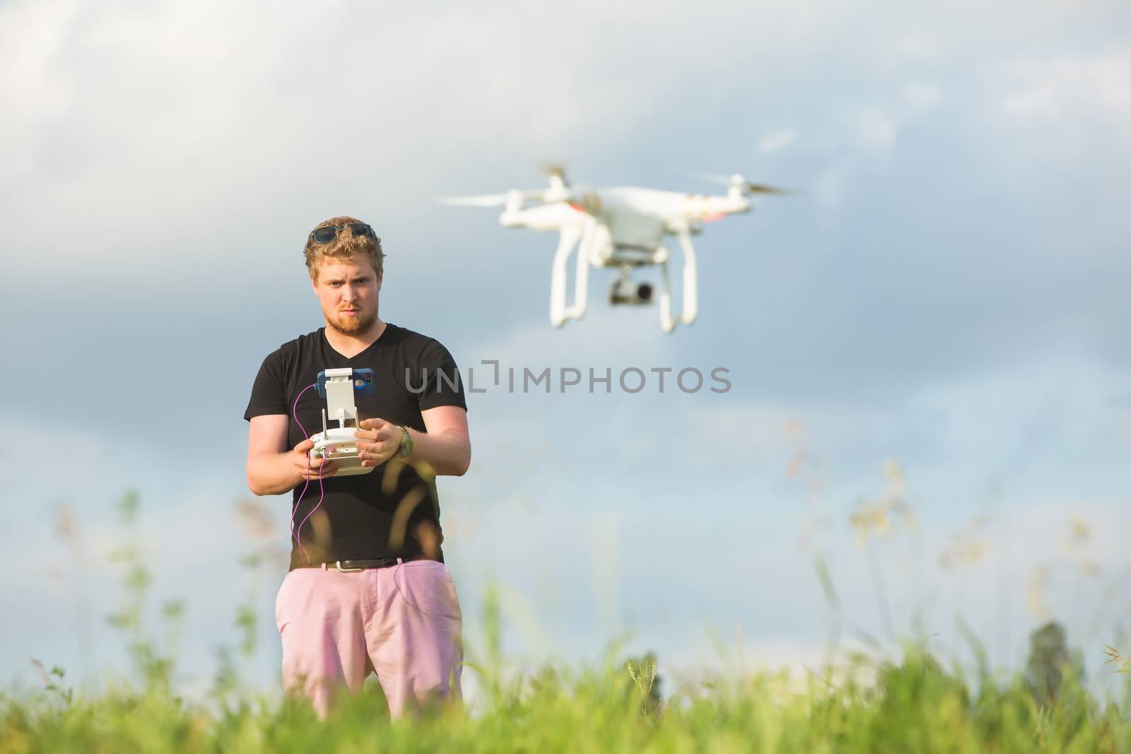 Man outdoors with remote control and flying surveillance drone