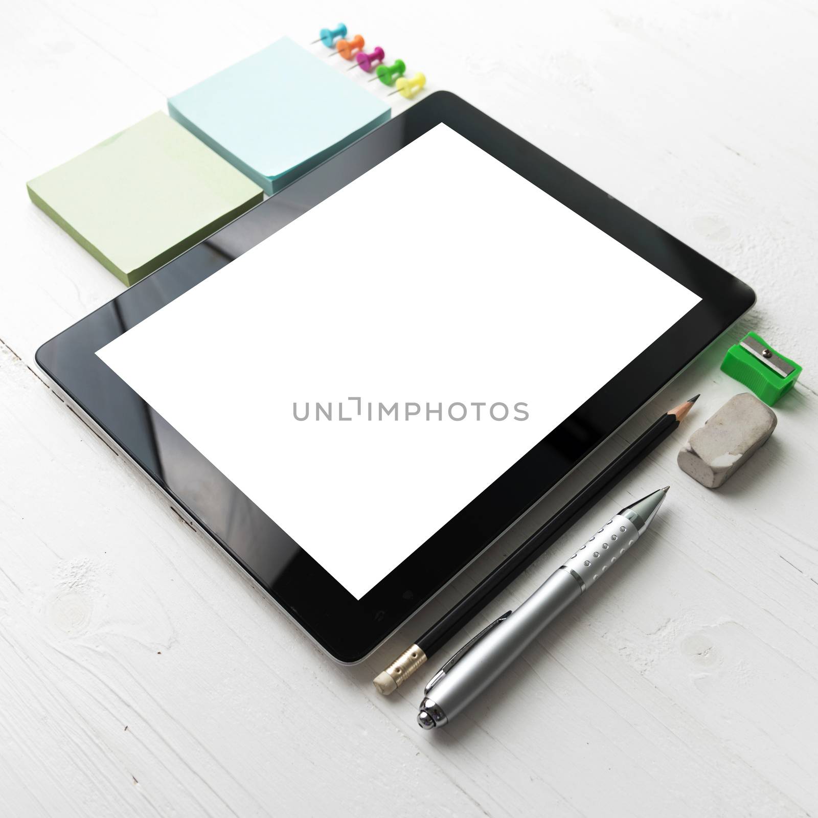tablet with office supplies over white table