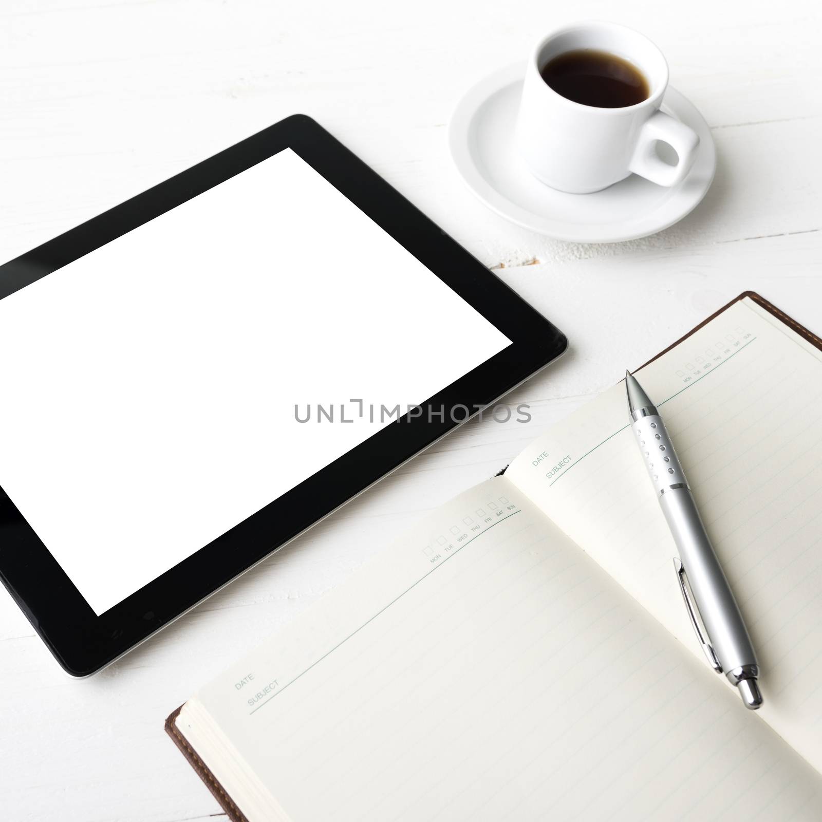 tablet with office supplies over white table