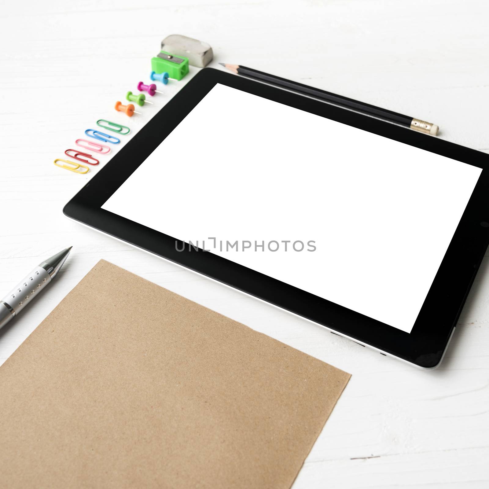 tablet with office supplies over white table