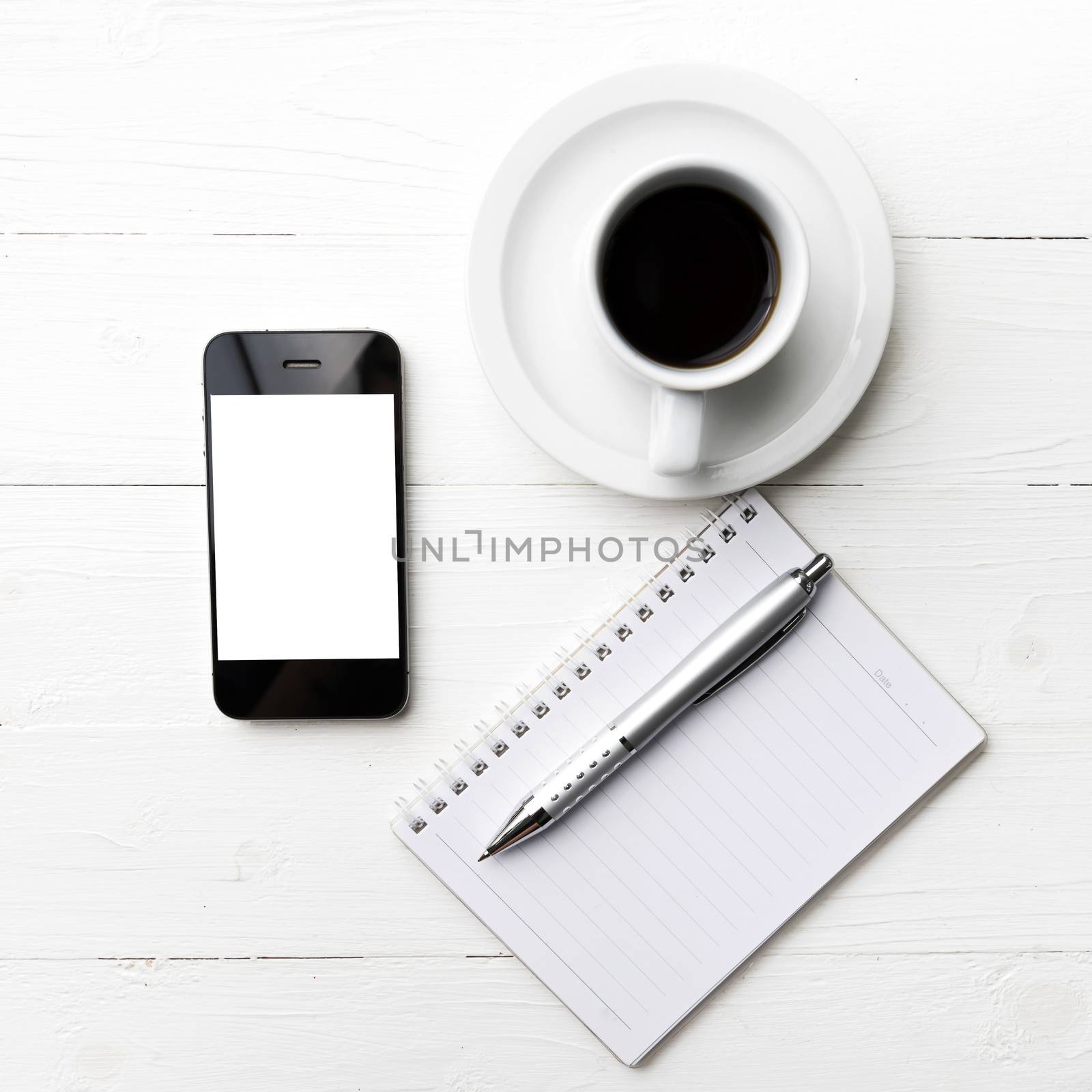 cellphone with notebook and coffee cup over white table