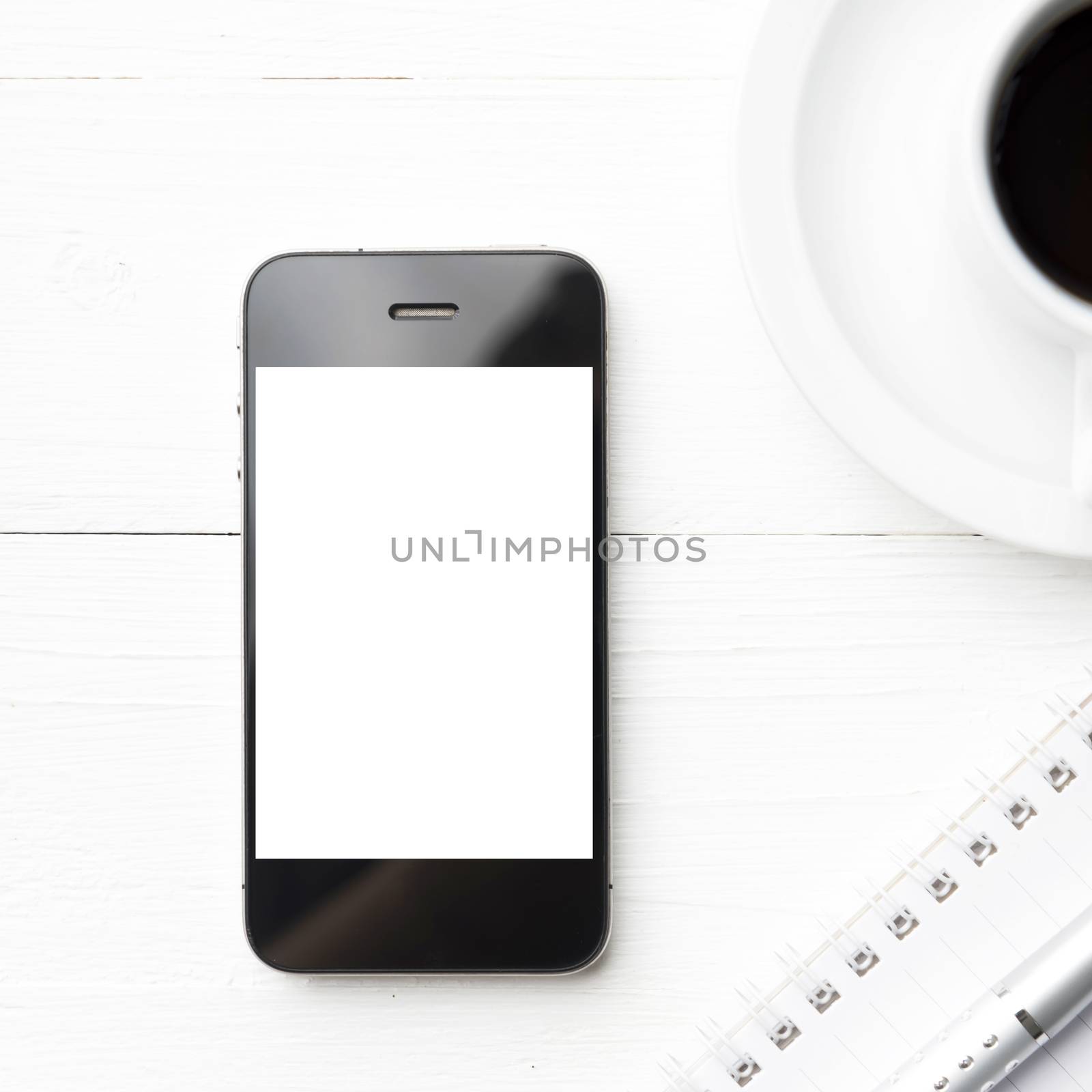 cellphone with notebook and coffee cup over white table