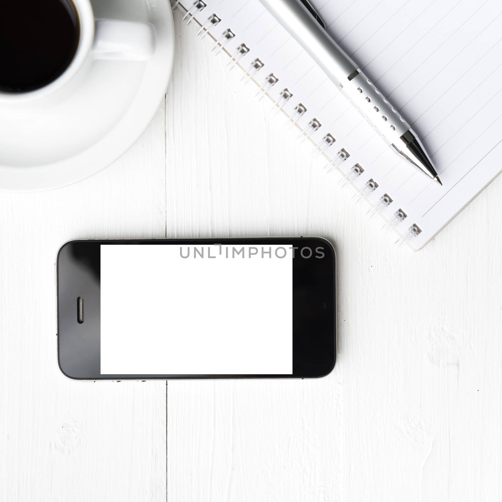 cellphone with notebook and coffee cup over white table