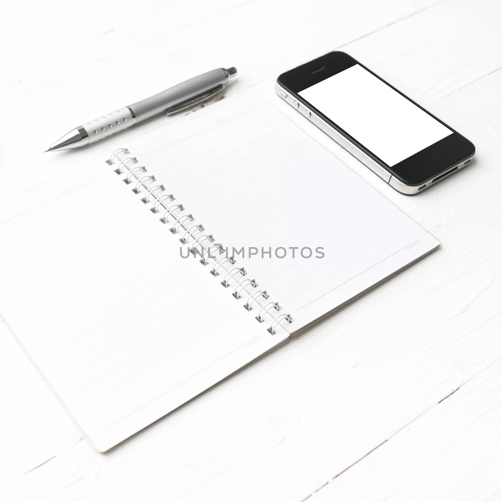 cellphone with notepad and pen over white table