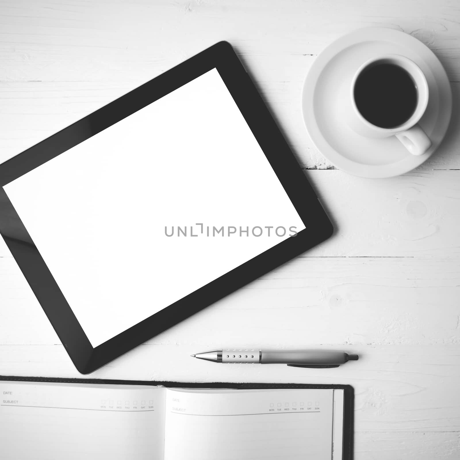 tablet with notebook and coffee cup over white table black and white color style