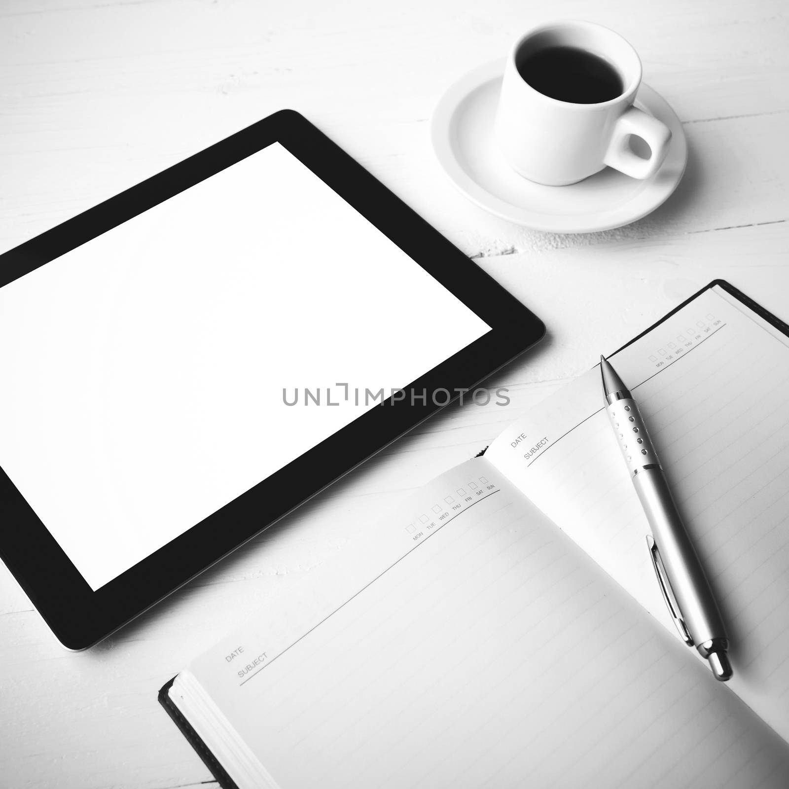 tablet with office supplies over white table black and white color style