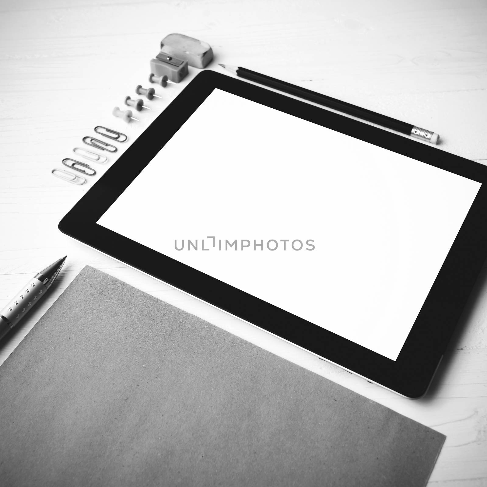 tablet with office supplies over white table black and white color style