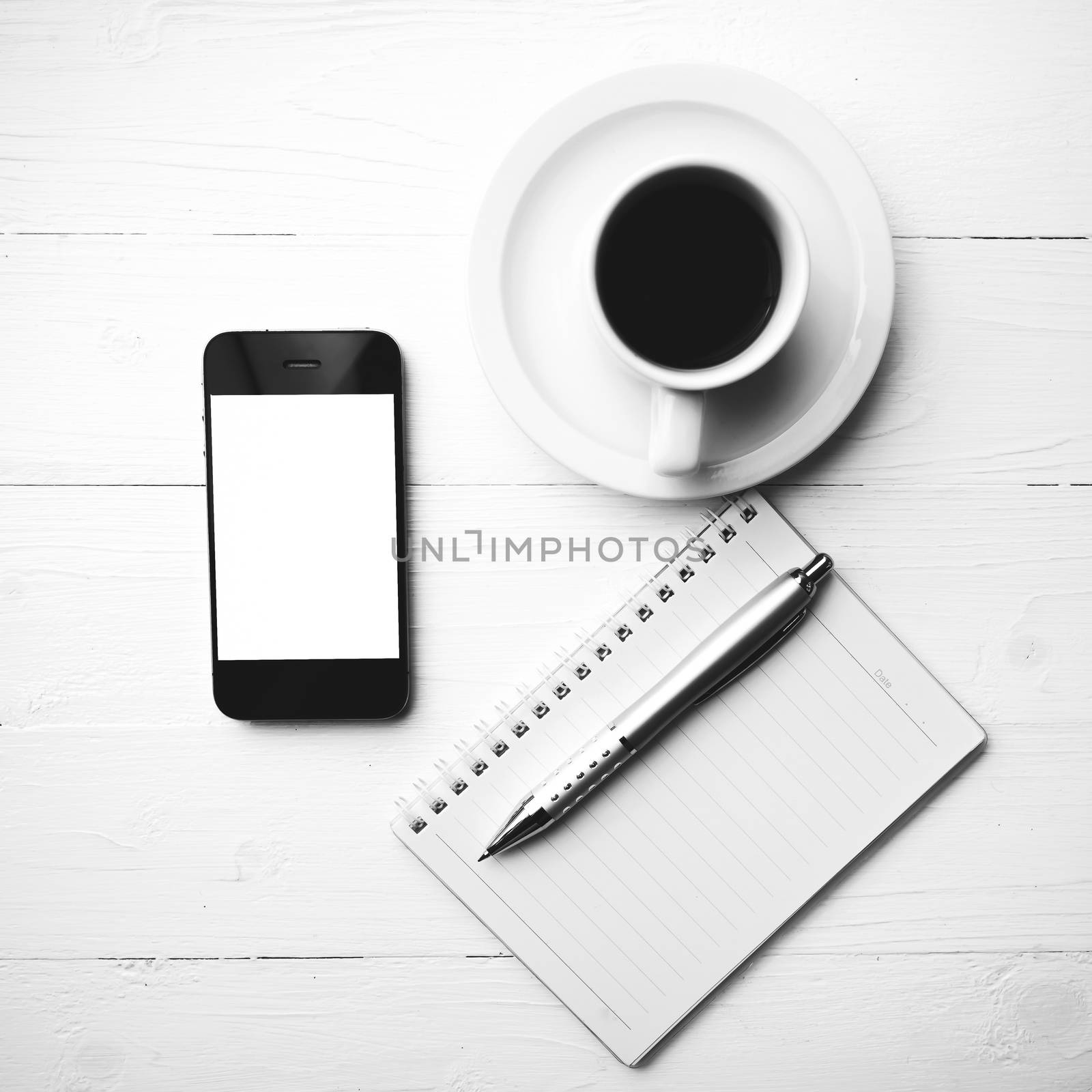 cellphone with notebook and coffee cup over white table black and white color style