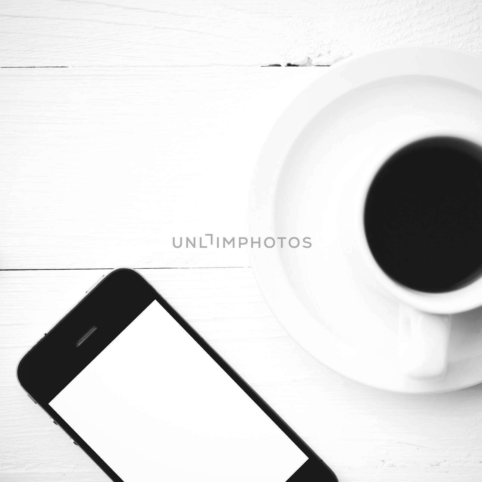 cellphone and coffee cup over white table black and white color style