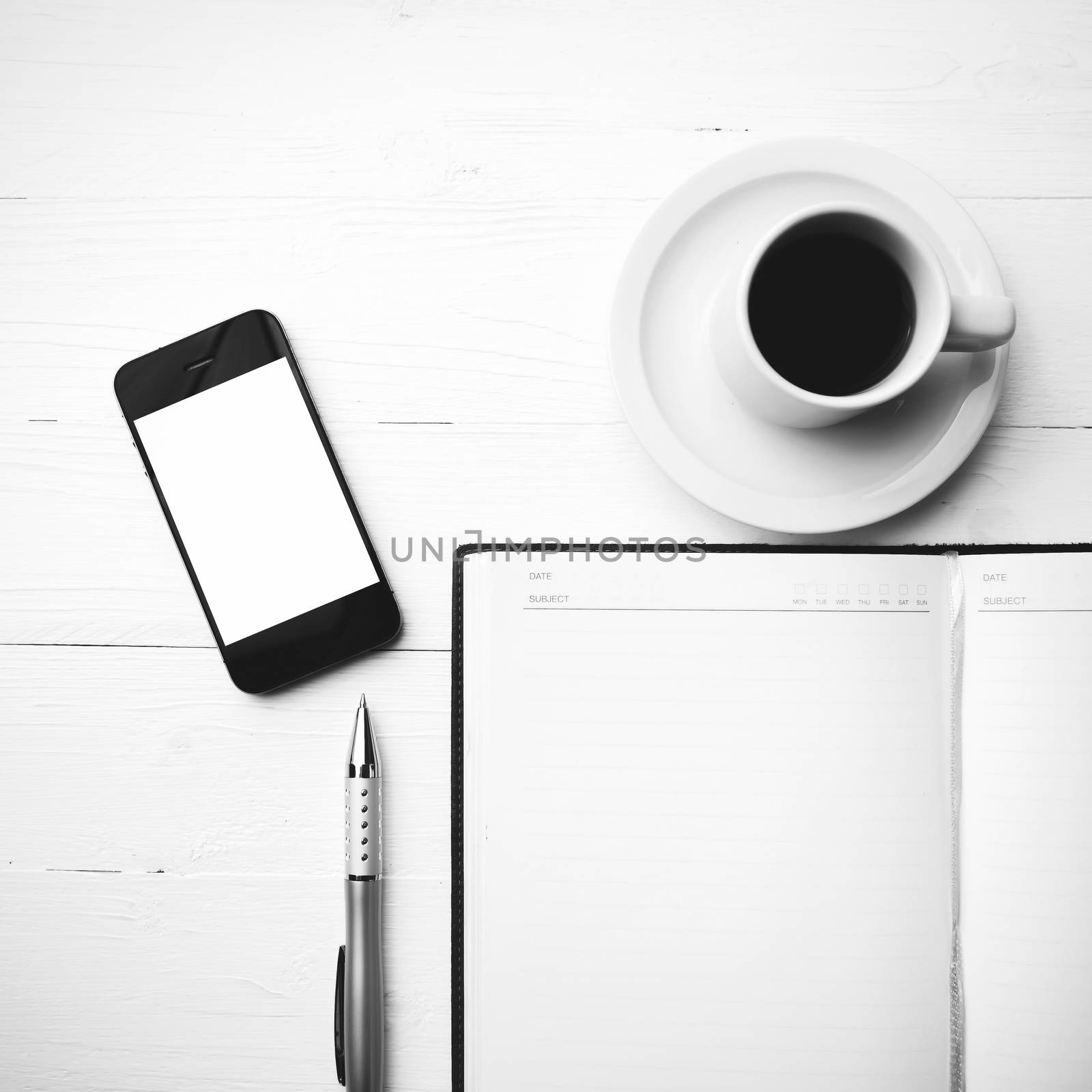 cellphone with notebook and coffee cup over white table black and white color style