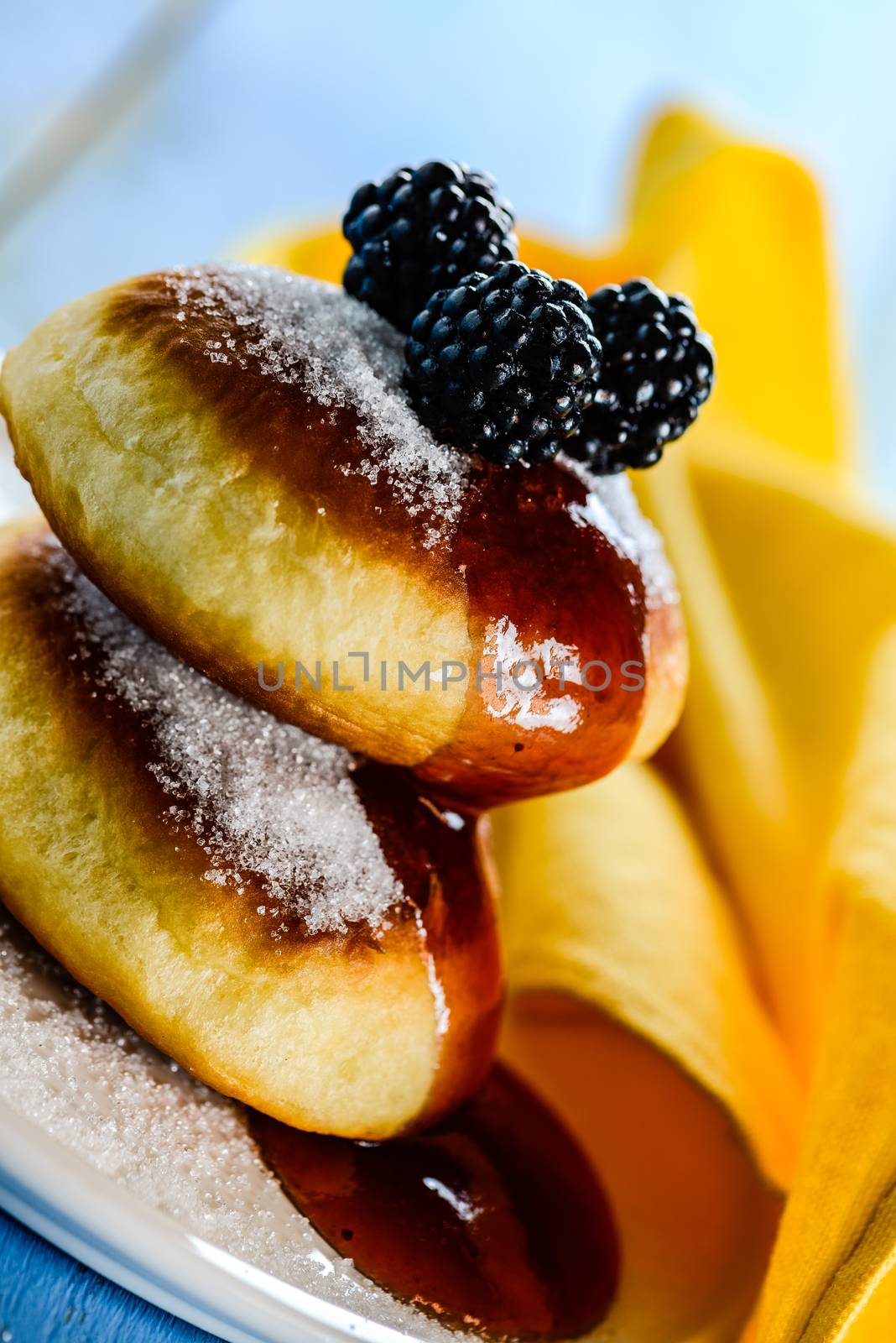 two delicious german doughnuts with blackberry and blackberry sauce on white plate