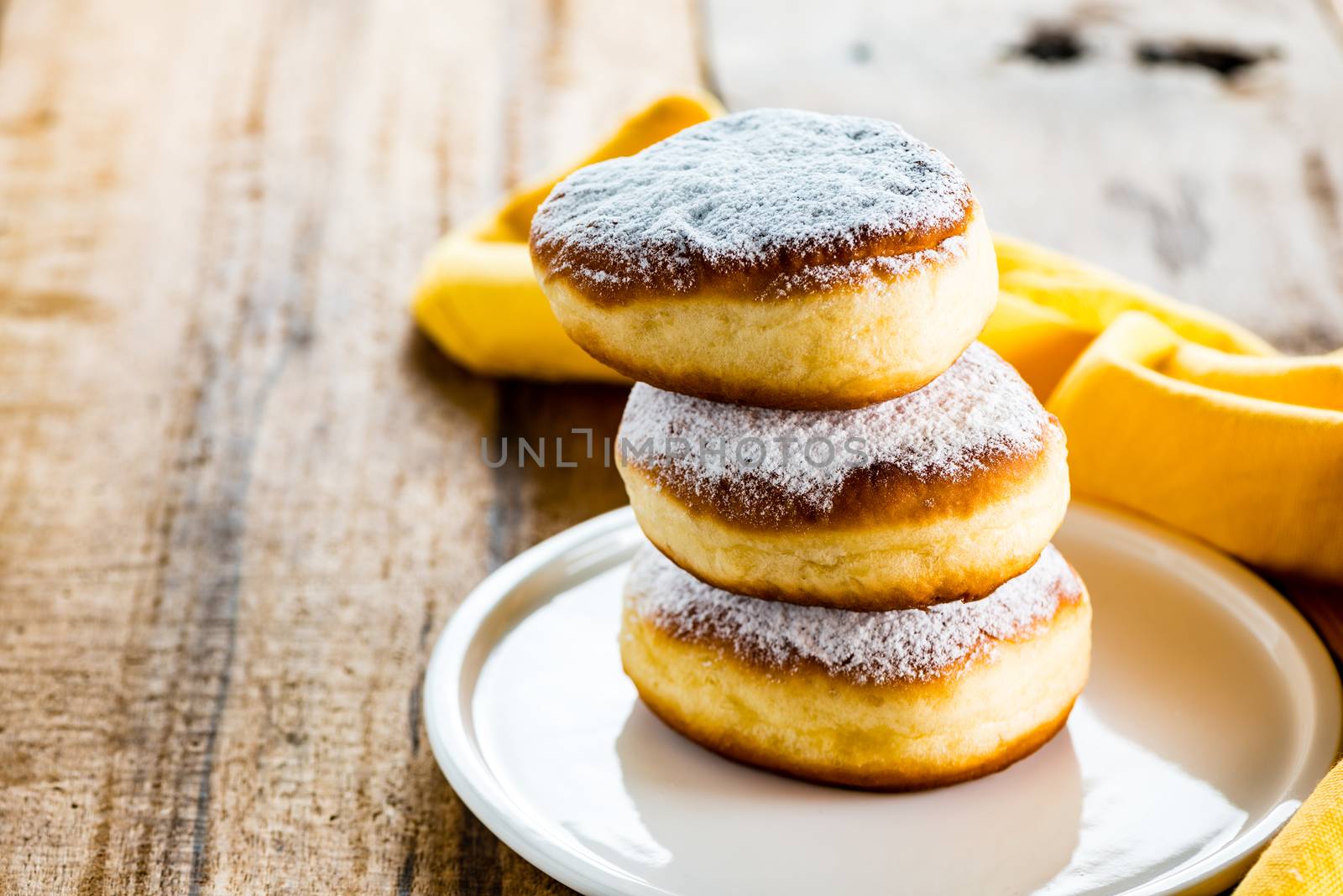 three delicious german doughnuts powdered with sugar on white plate