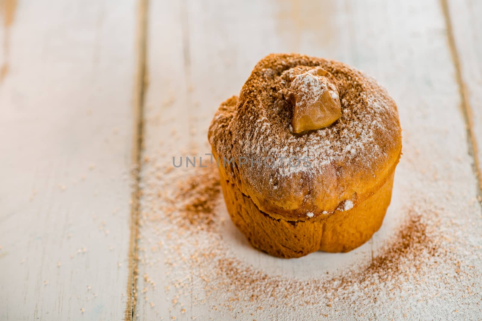 Small cakes with apple powdered with cinnamon and sugar on white wood table
