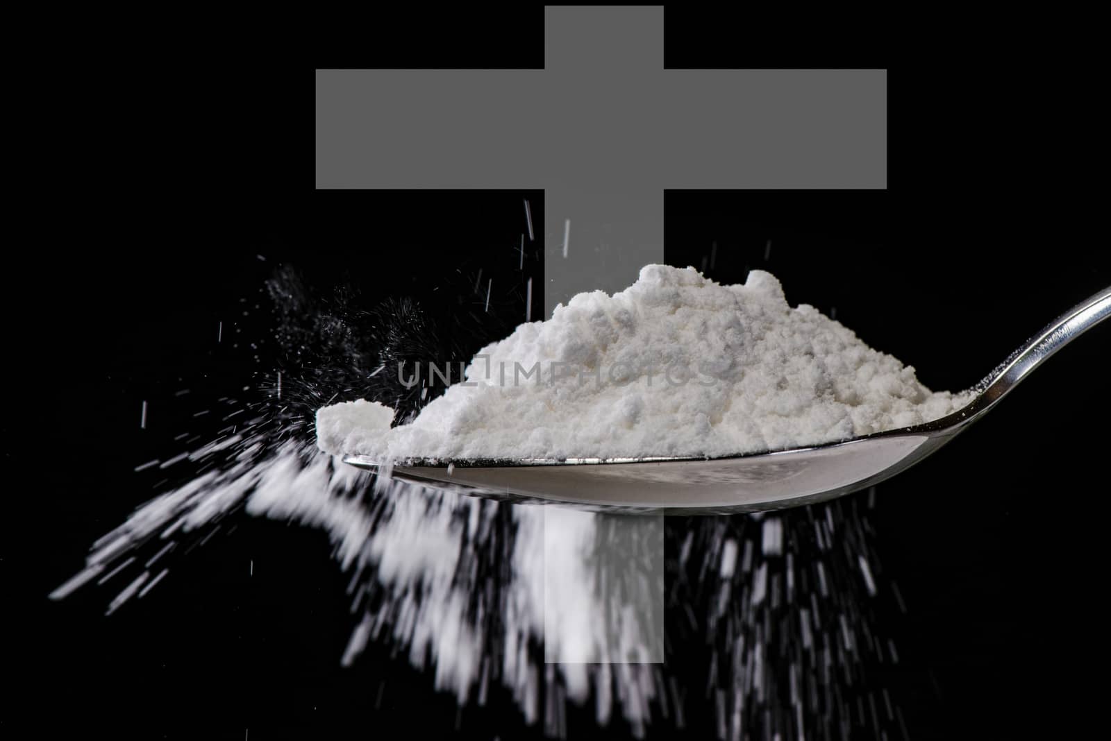 white powder in spoon like drug or medicine with a cross in background as sign for death