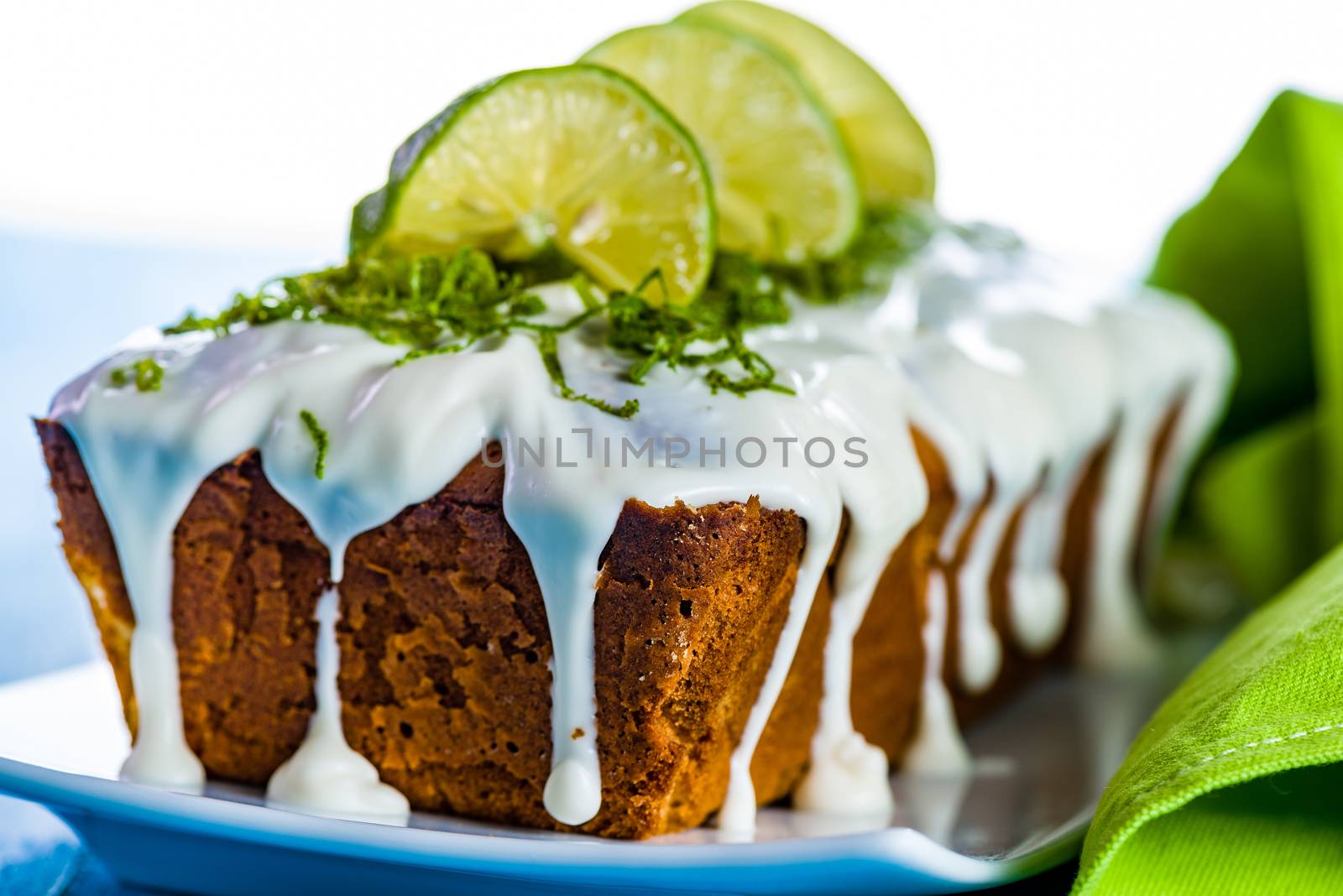 lemon loaf cake with icing decorating with lemon on white plate and blue wood table