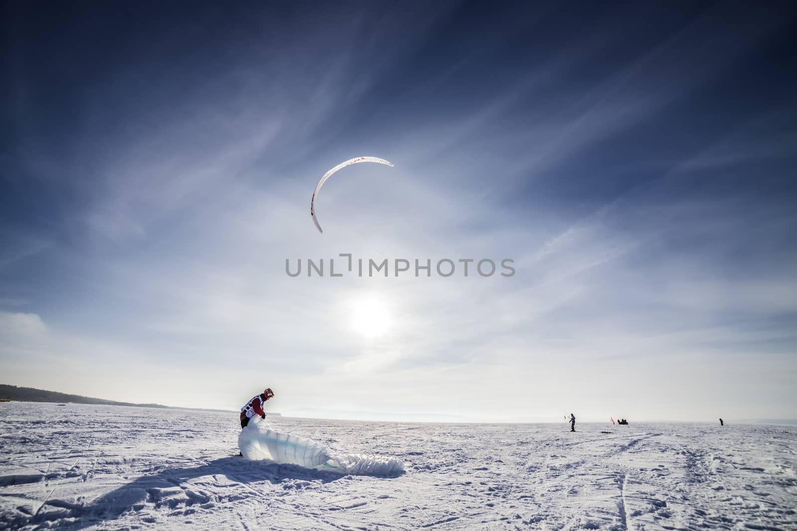 Kite surfer being pulled by his kite across the snow