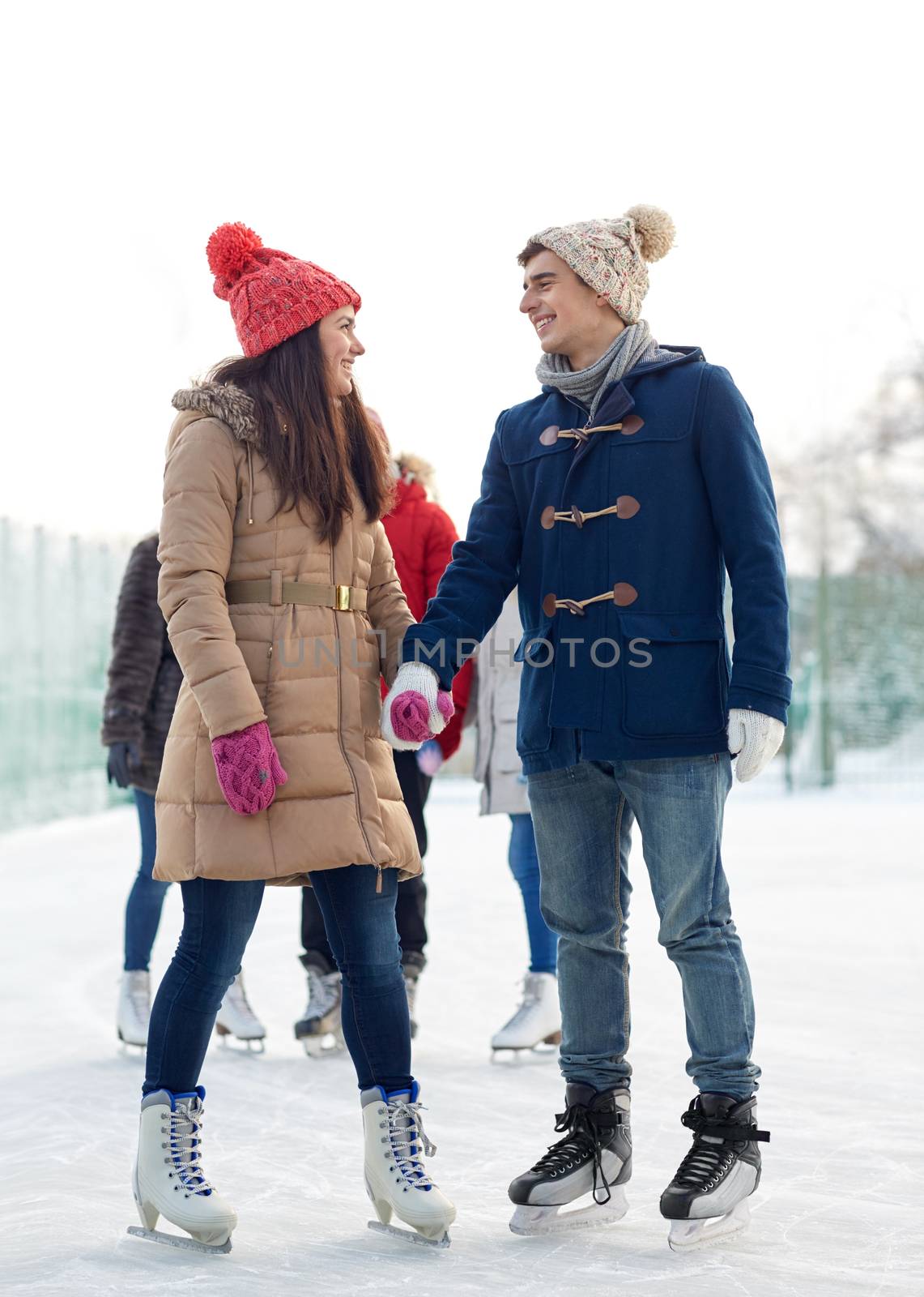 happy friends ice skating on rink outdoors by dolgachov